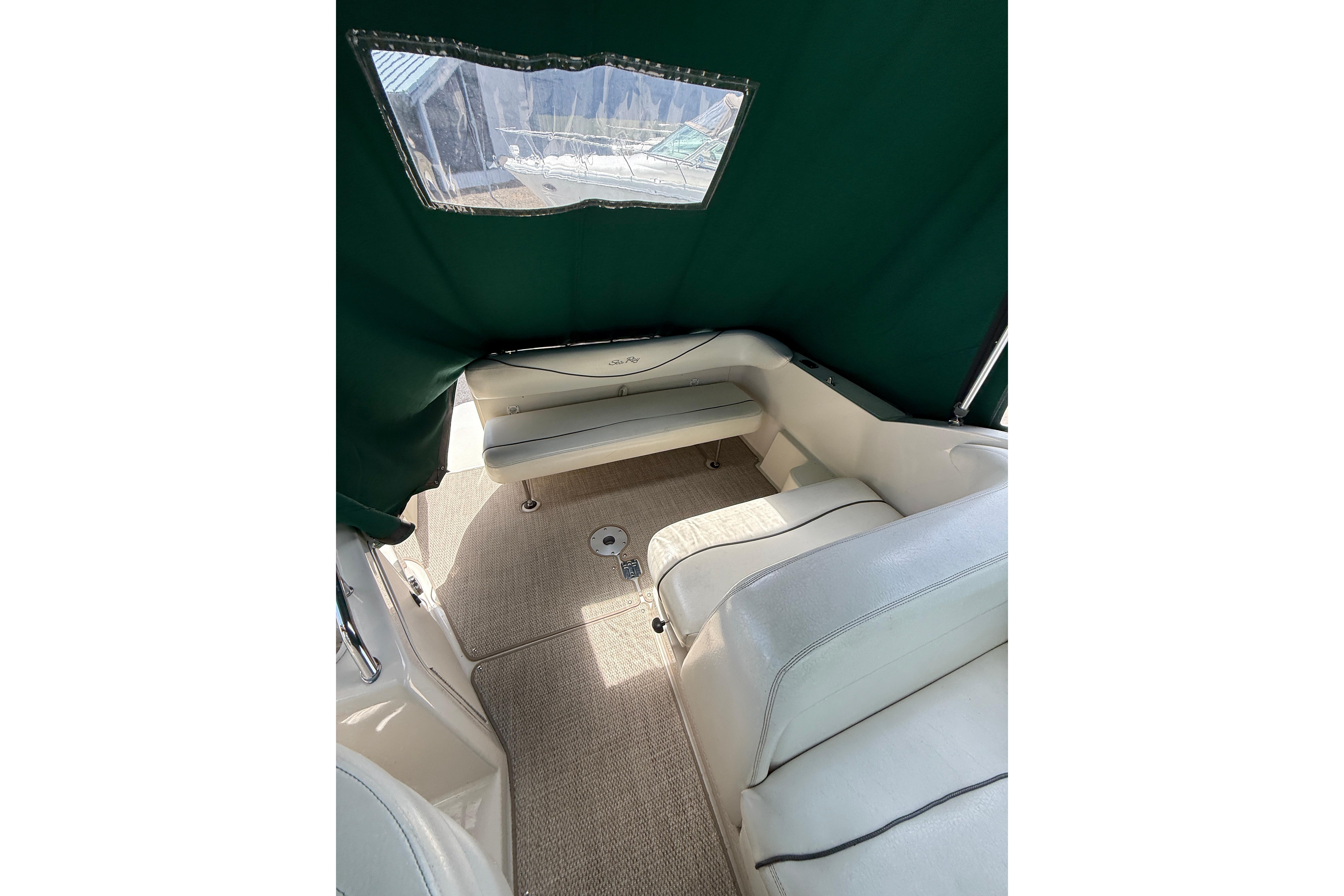 Interior view of 2004 Sea Ray 240 Sundancer with green canopy and white seating.