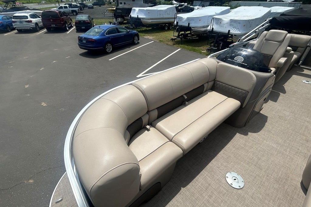 2023 Sun Tracker Party Barge 22 DLX with beige seating in a parking lot.