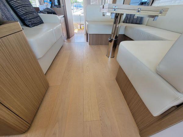 Luxurious interior of 2019 Absolute 50 Fly yacht with wooden flooring and white seating.