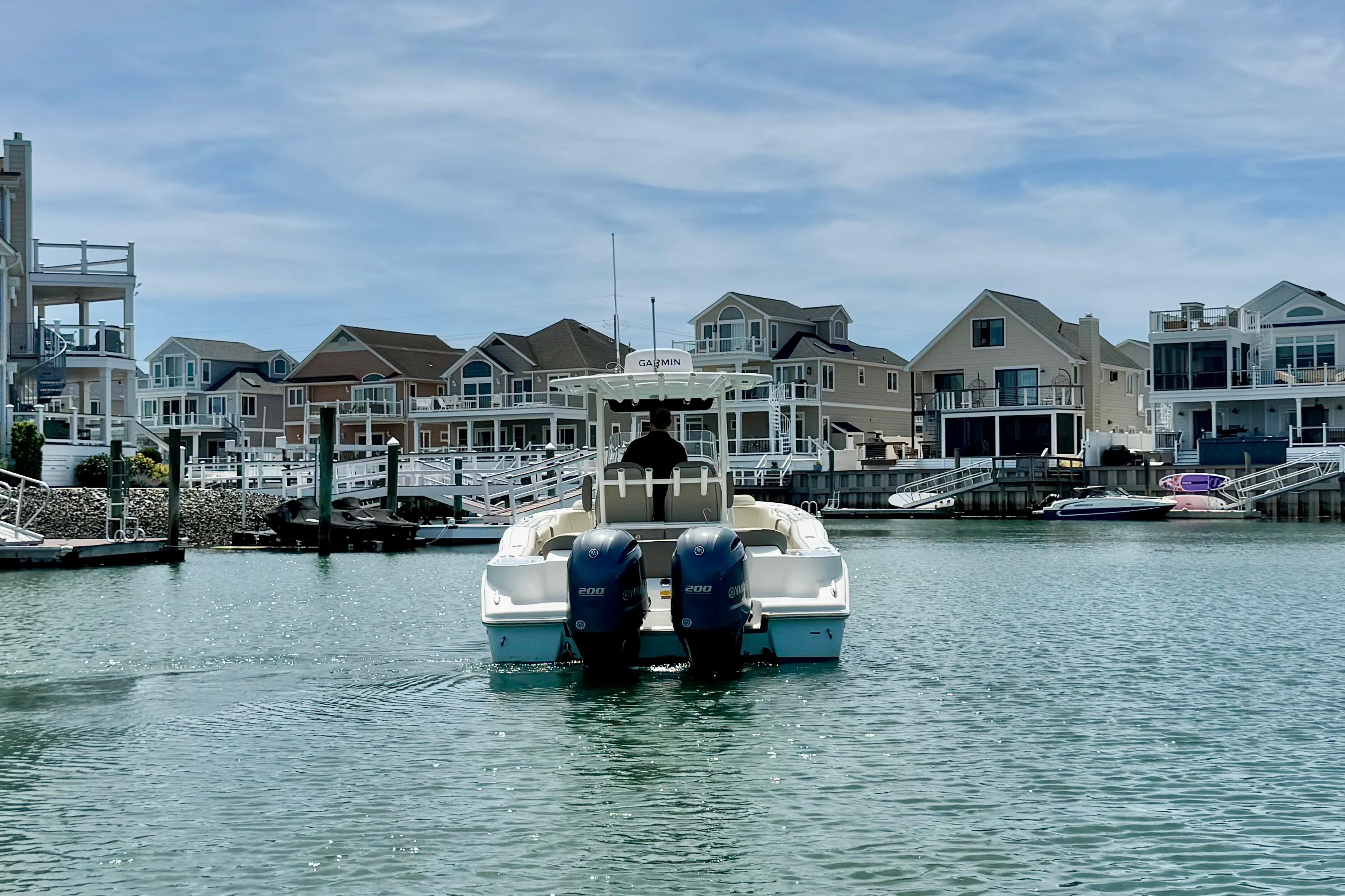 2022 Key West 263 FS boat cruising in a scenic waterfront neighborhood.