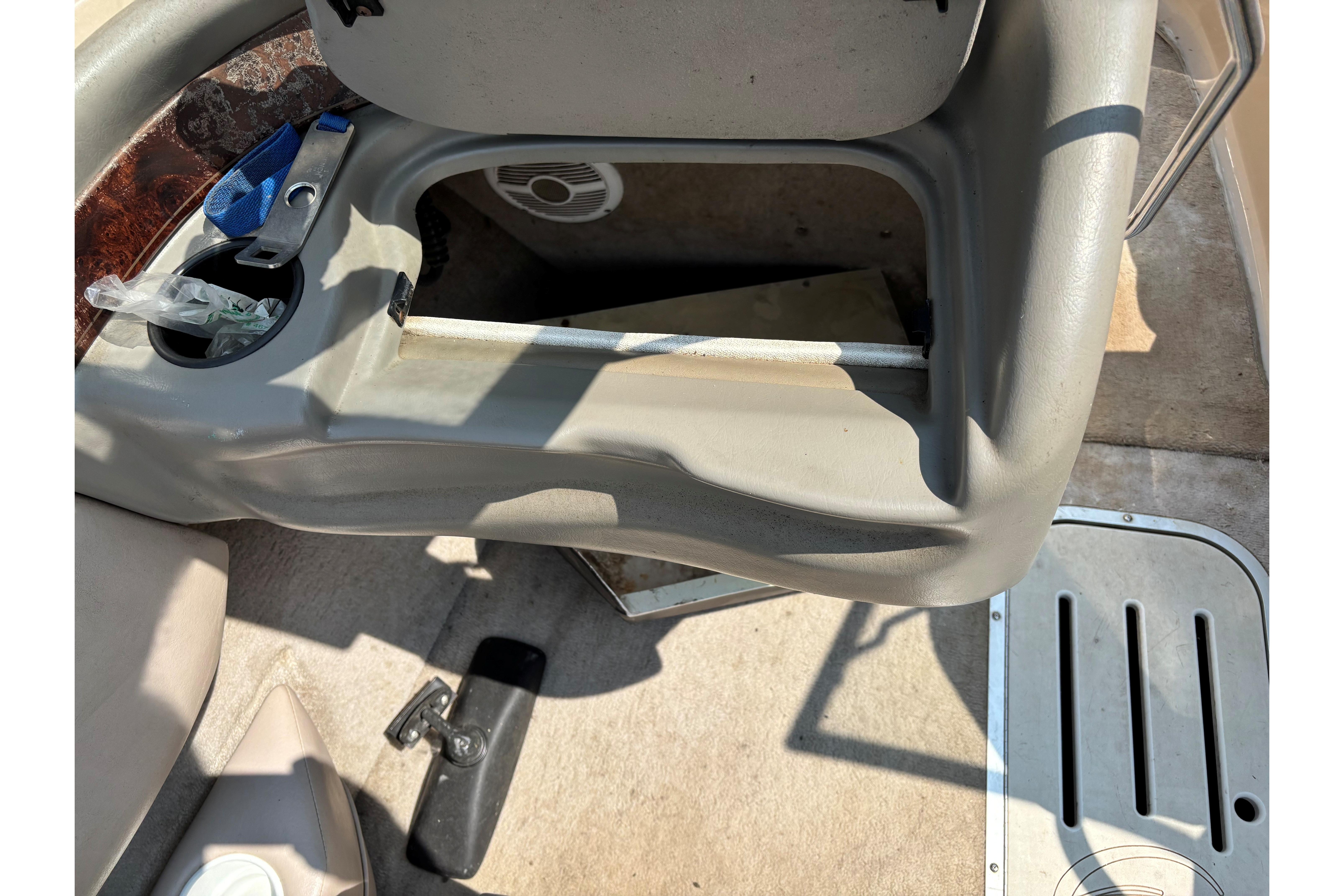 Interior of a 2001 Crownline 18' boat showing storage compartment and cup holder.