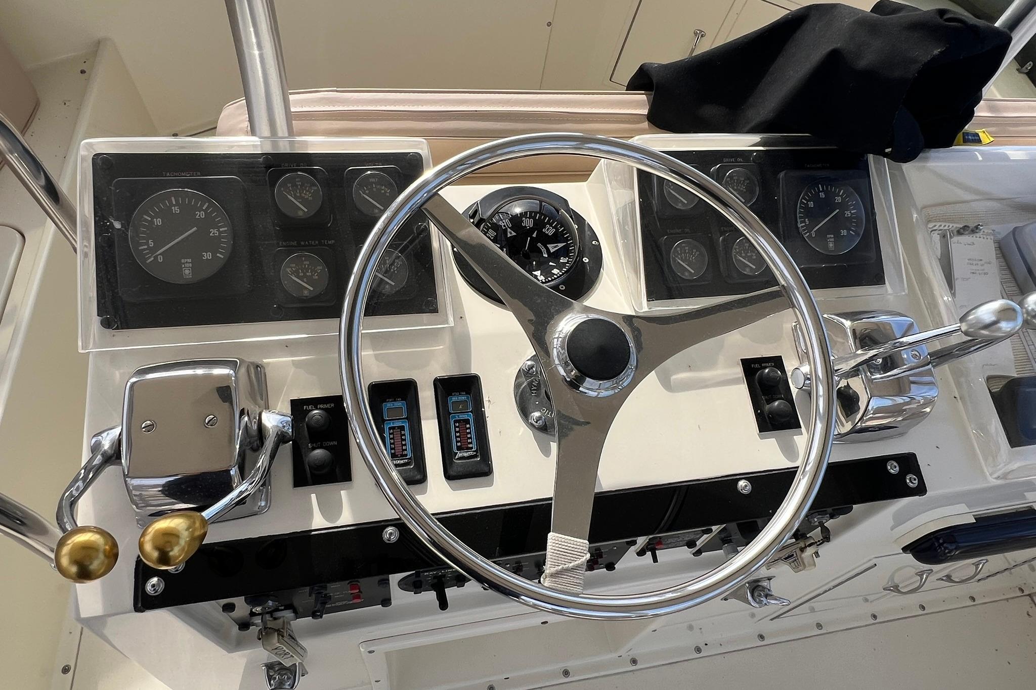 Control panel of a 1990 Hatteras 41 Convertible boat with steering wheel and gauges.