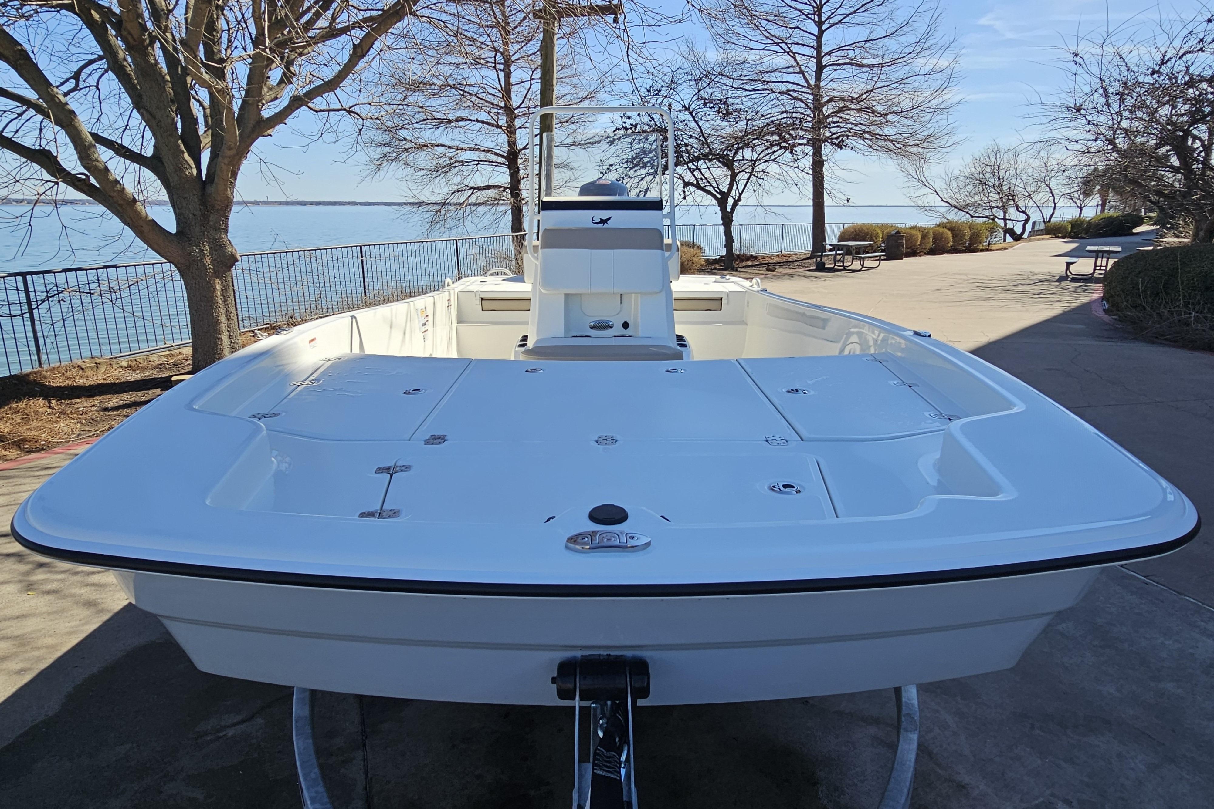 2026 Mako Pro Skiff 19 CC boat docked by a scenic lakeside.
