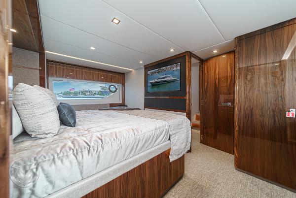 Luxurious bedroom interior of 2025 Riviera 645 SUV yacht with wooden finishes and large window.