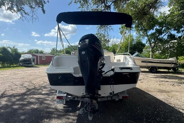 1999 Hurricane SunDeck Sport 201 OB boat with outboard motor, parked outdoors under trees.