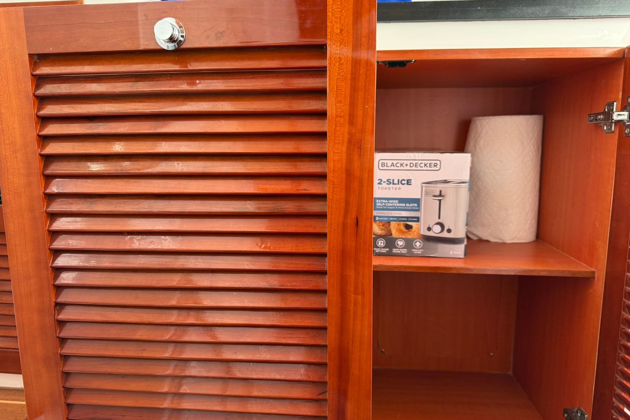 Wooden cabinet on SeaPiper 35 yacht, containing a toaster box and paper towel roll.