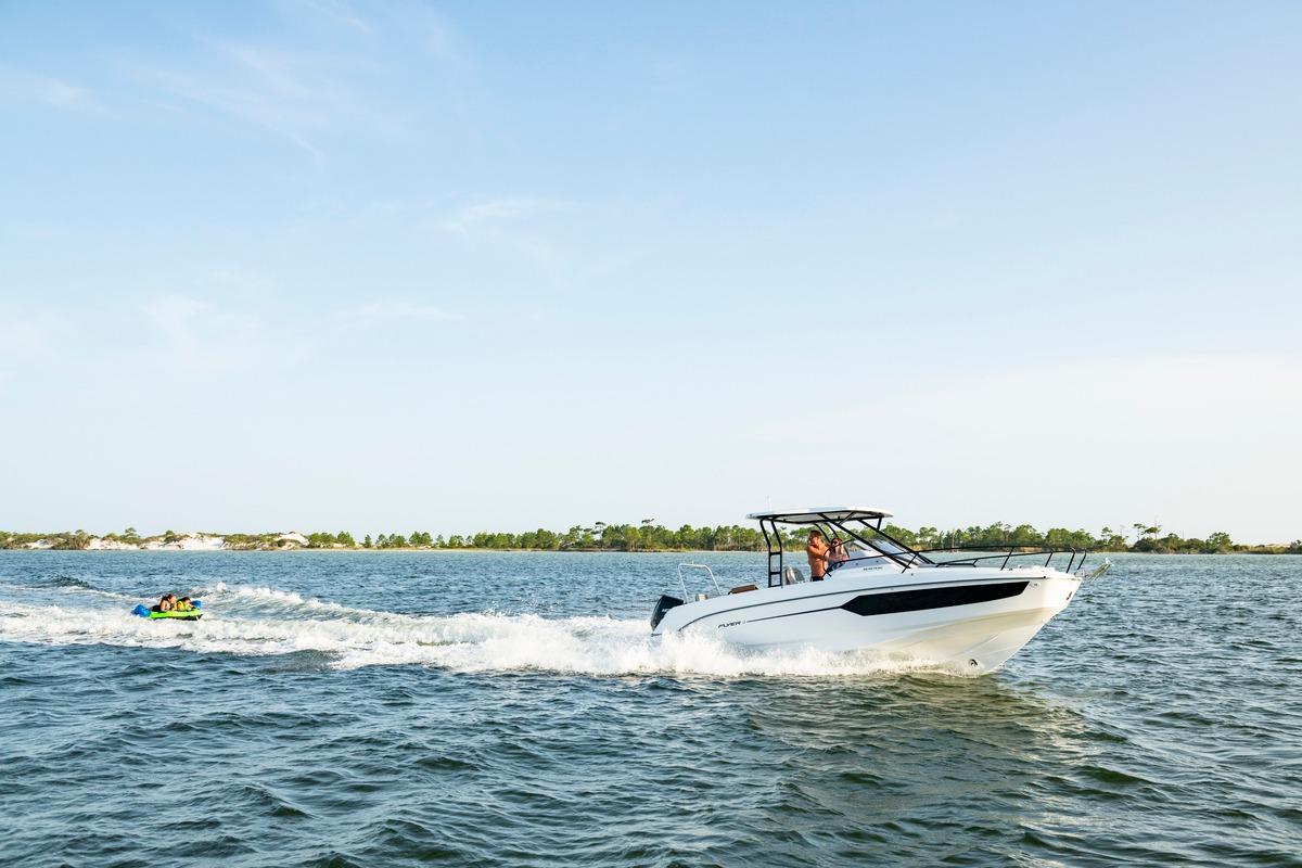 2026 Beneteau Flyer 8 SUNdeck cruising on open water, towing a tube with passengers.