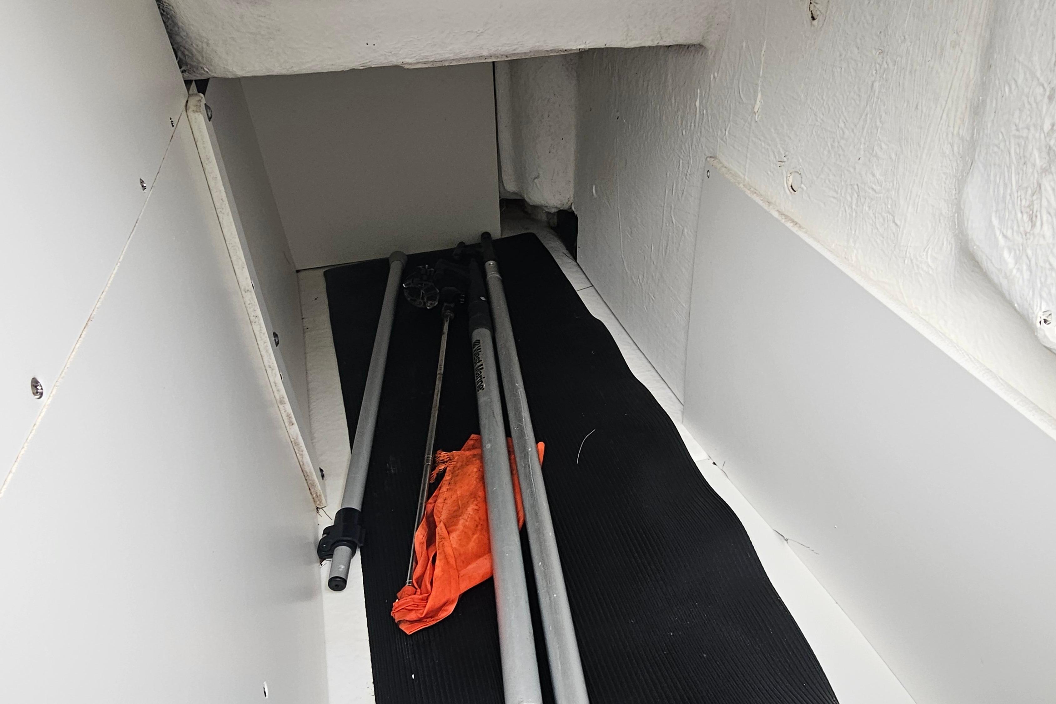 Storage compartment in a 2017 Sea Ray SDX 240 Outboard boat with poles and orange fabric.