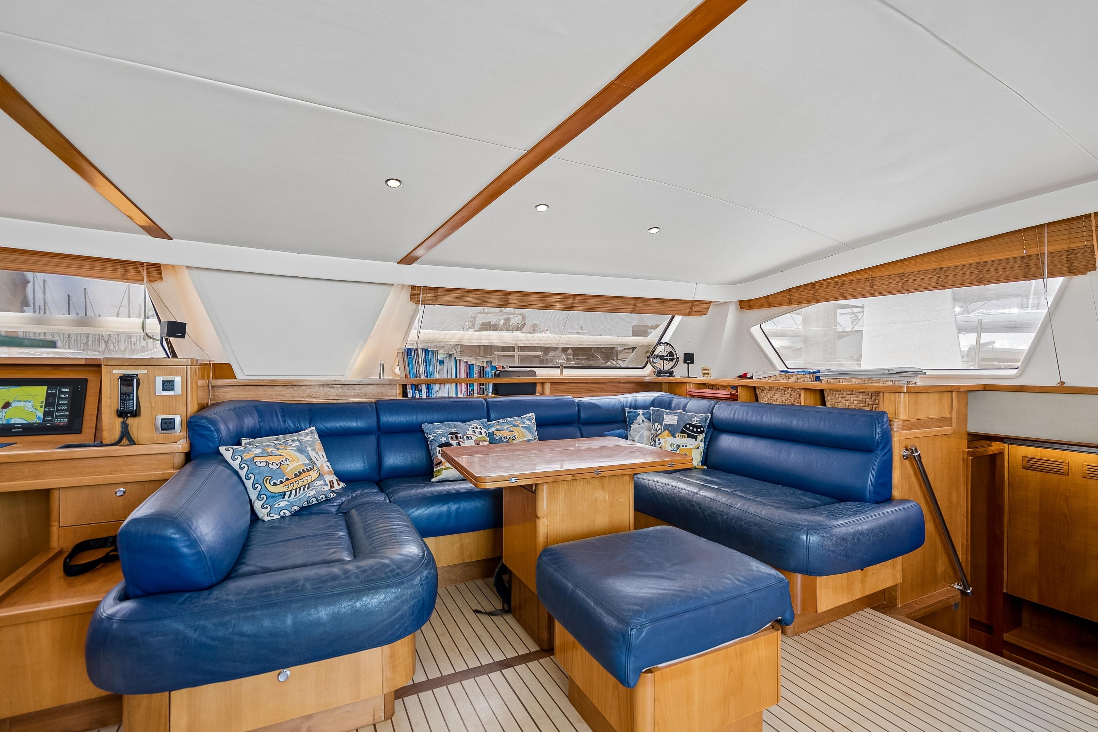 Luxurious 2009 Catana 65 yacht interior with blue leather seating and wooden accents.