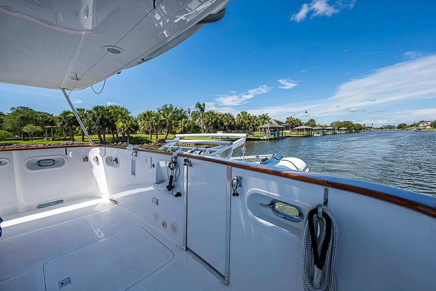 Magna Marine Nova Scotia 47 yacht deck, 2003 model, overlooking serene waterfront and lush greenery.