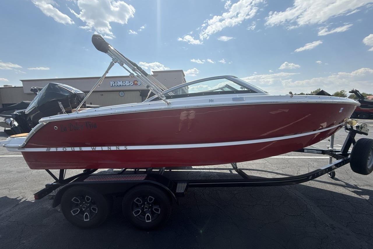 2024 Four Winns H1 OB boat on trailer, red hull, sunny day.