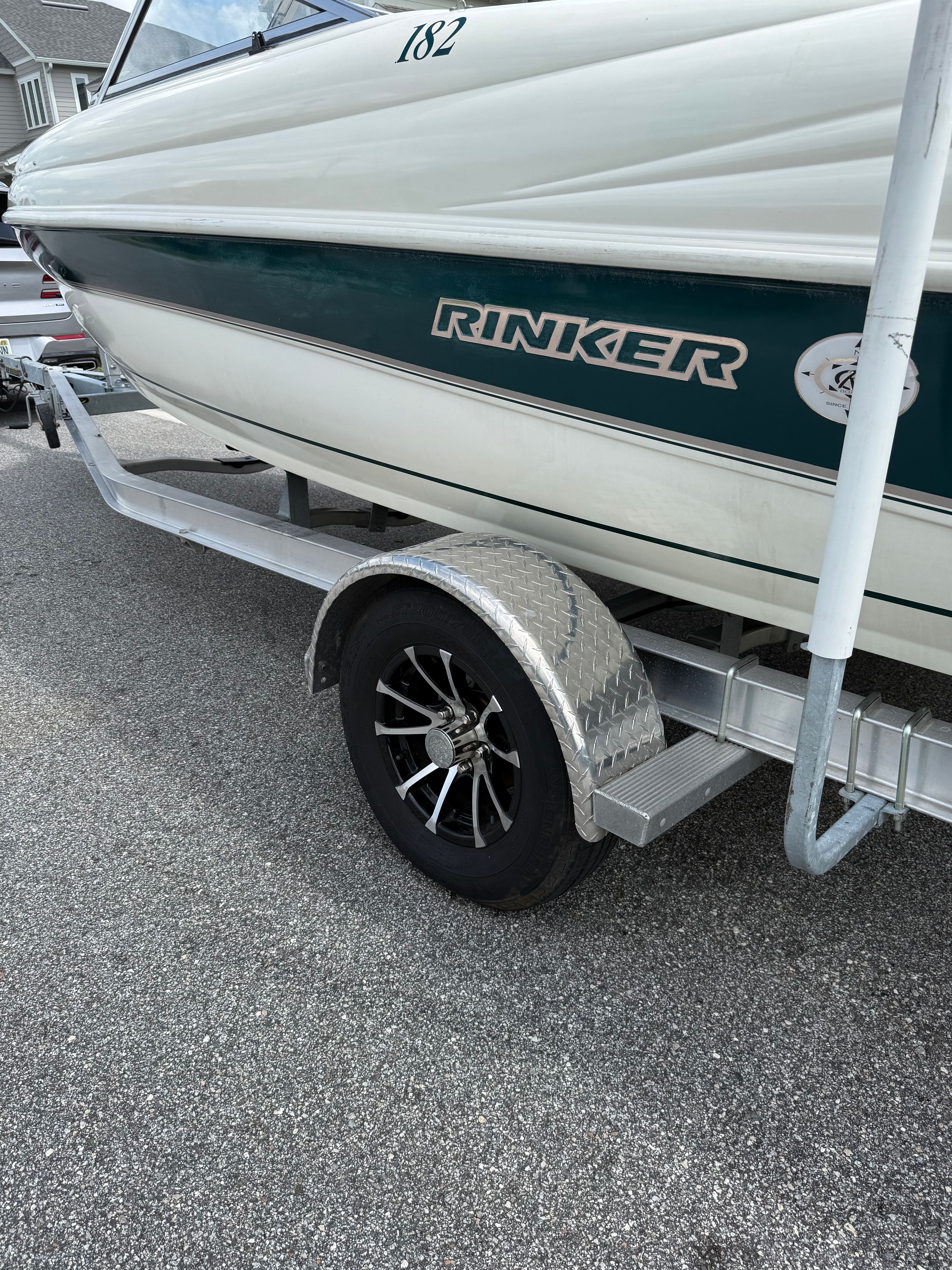 A Rinker Captiva boat on a trailer, parked on a driveway.