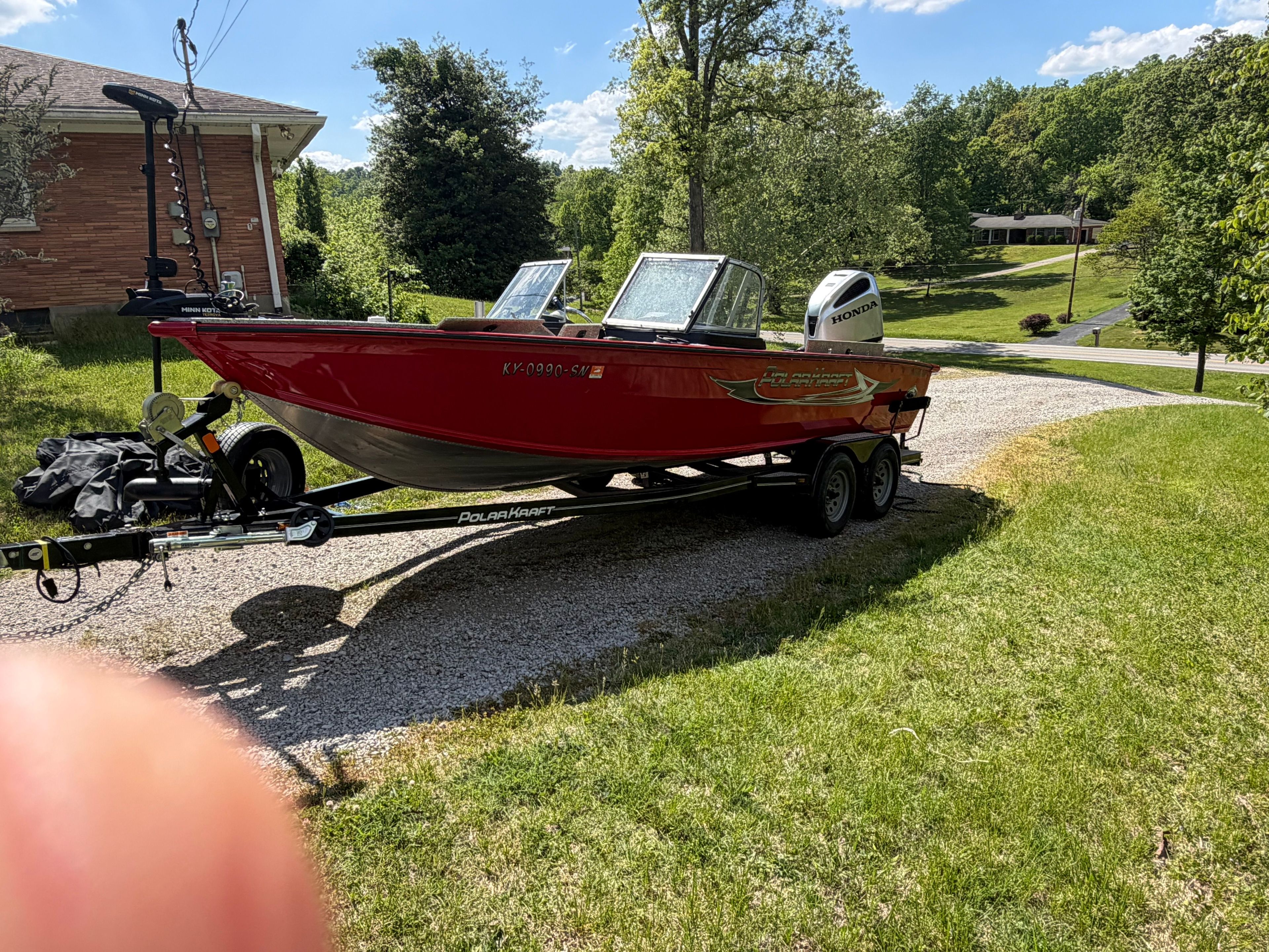 Red Polar Kraft Outlander 2010 boat, 2024 model, on trailer in yard.