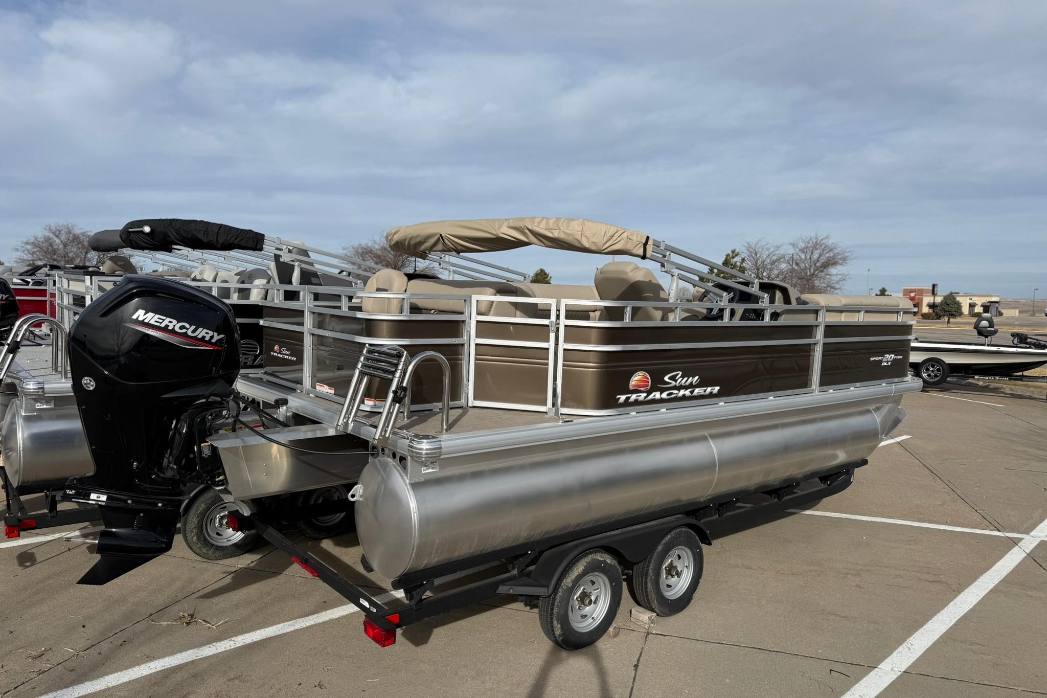 2025 Sun Tracker SportFish 20 DLX pontoon boat with Mercury outboard motor in parking lot.
