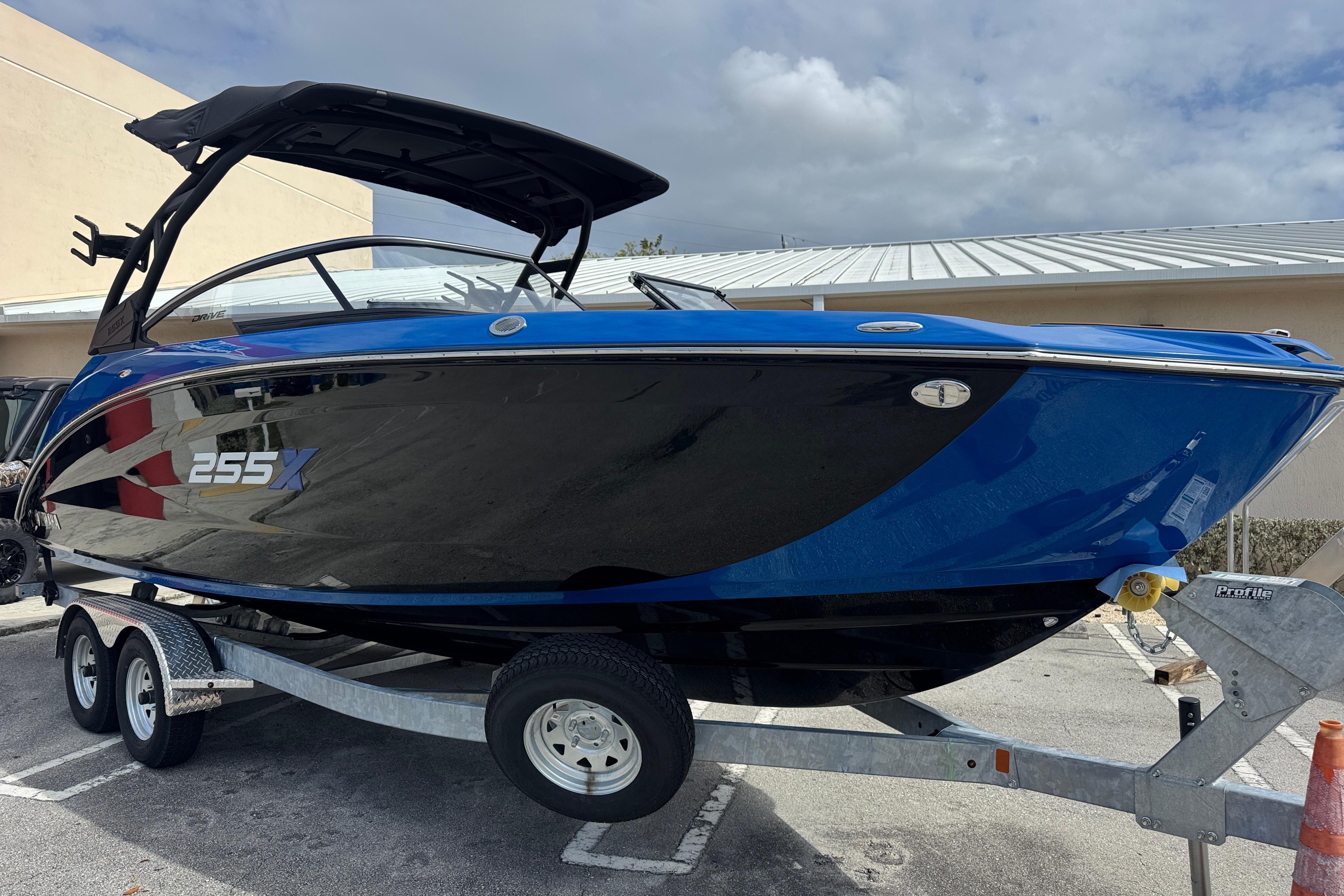 2026 Yamaha Boats 255XD in blue and black on a trailer, parked outdoors.