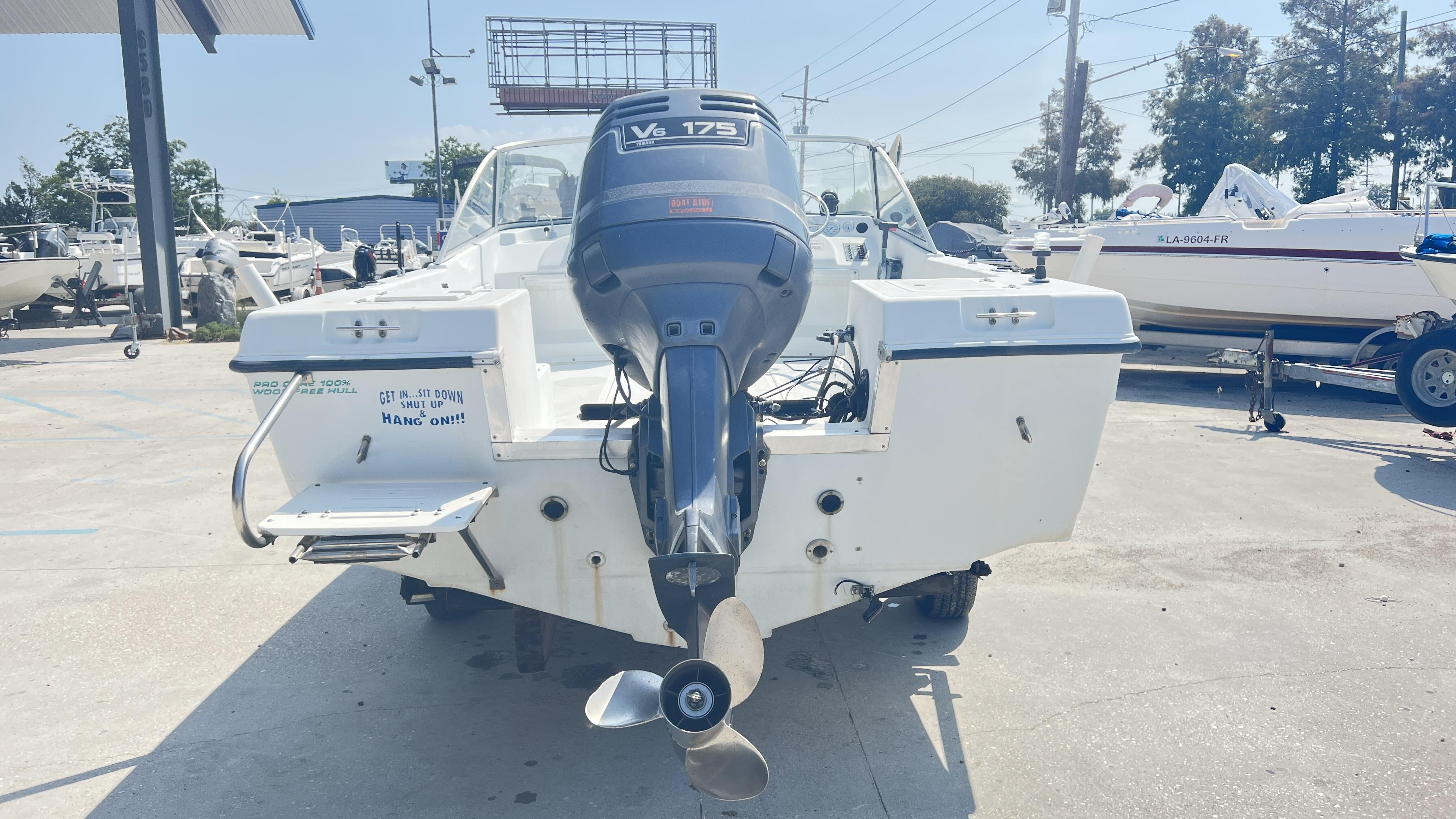 1998 Pro Sports Walk Through boat with outboard motor in a marina setting.