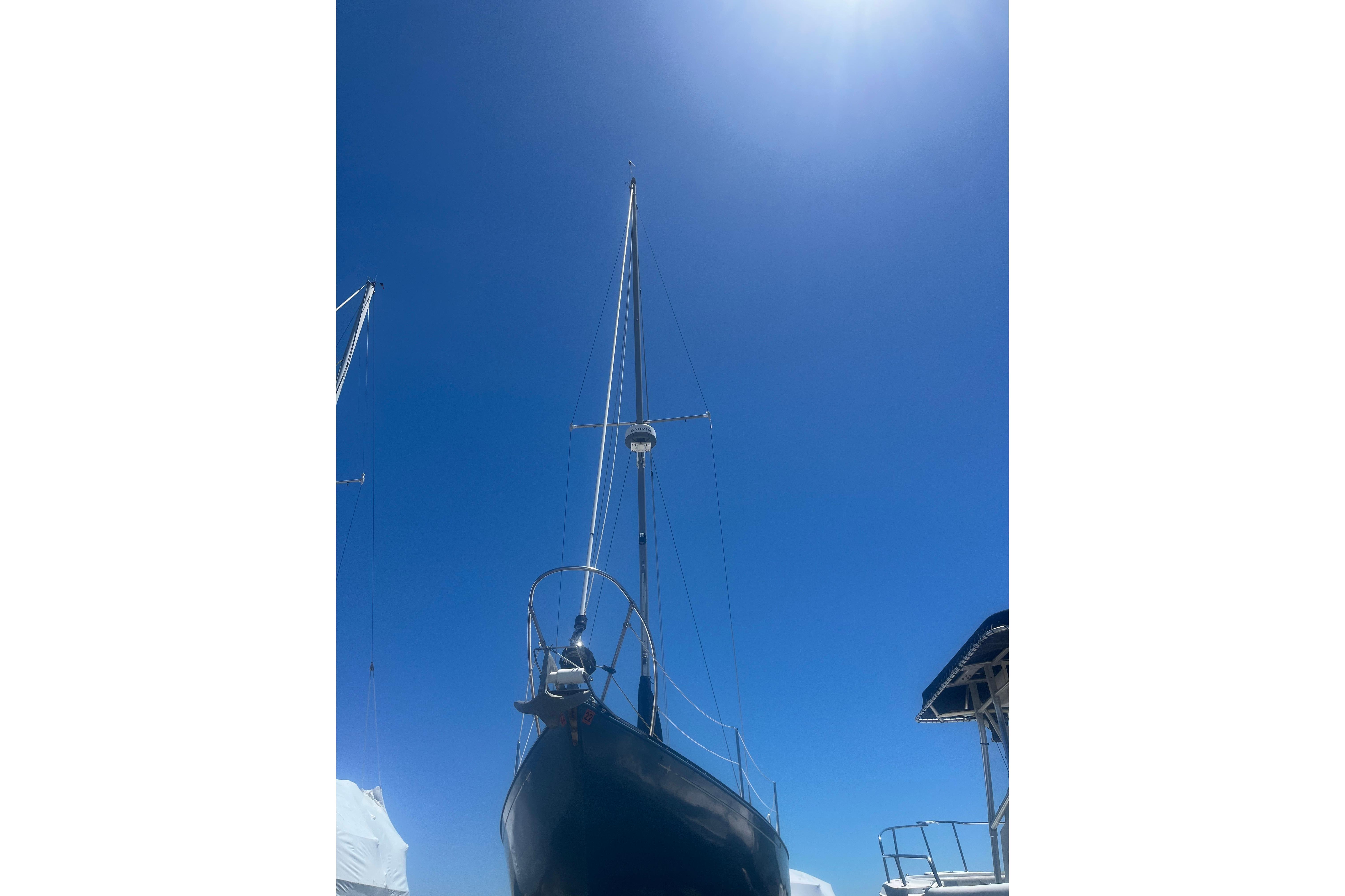 1972 C&C 30 sailboat under clear blue sky, viewed from below.