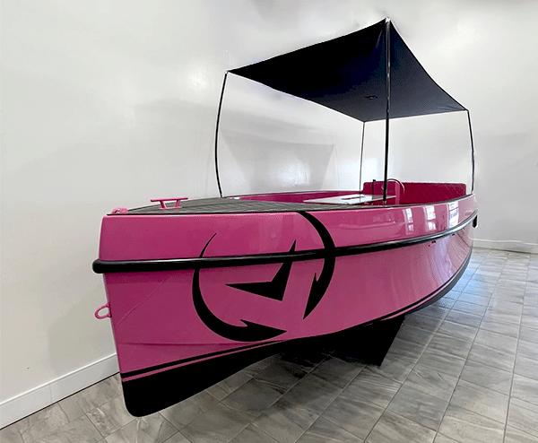 2023 Vision Marine Technologies Volt 180, pink electric boat with canopy, displayed indoors.