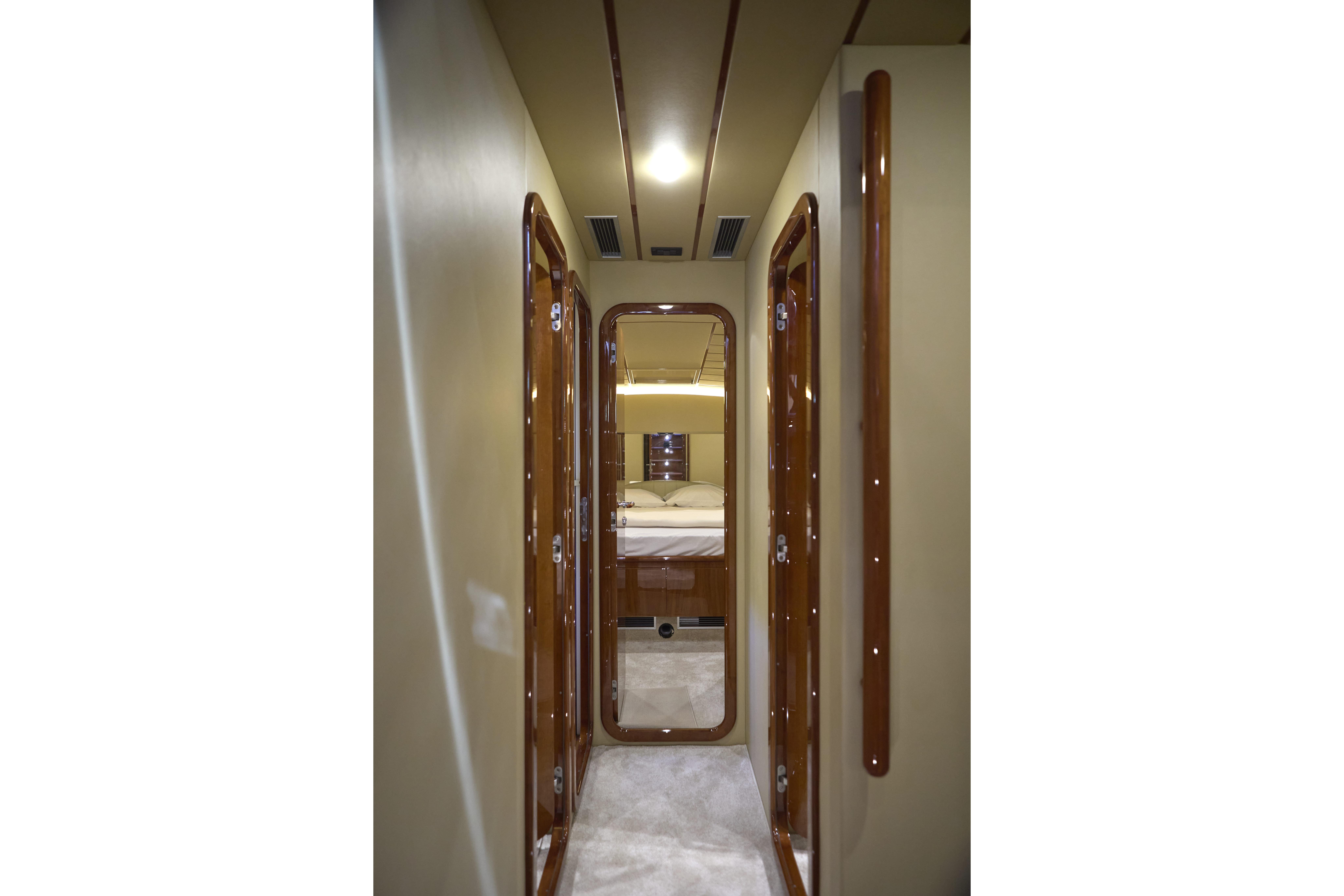 Narrow hallway inside 2004 Ferretti Yachts 680, featuring polished wood doors and soft lighting.