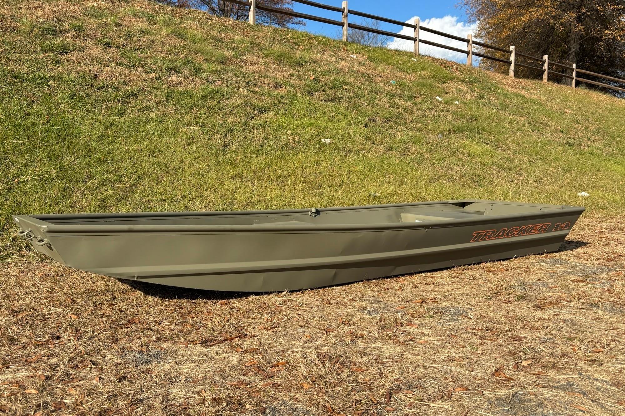 2026 Tracker Grizzly 14 Jon boat on grassy terrain, under clear blue sky.