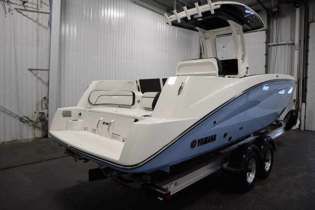 2026 Yamaha Boats 255 FSH Sport E in a garage, showcasing sleek design and dual-axle trailer.
