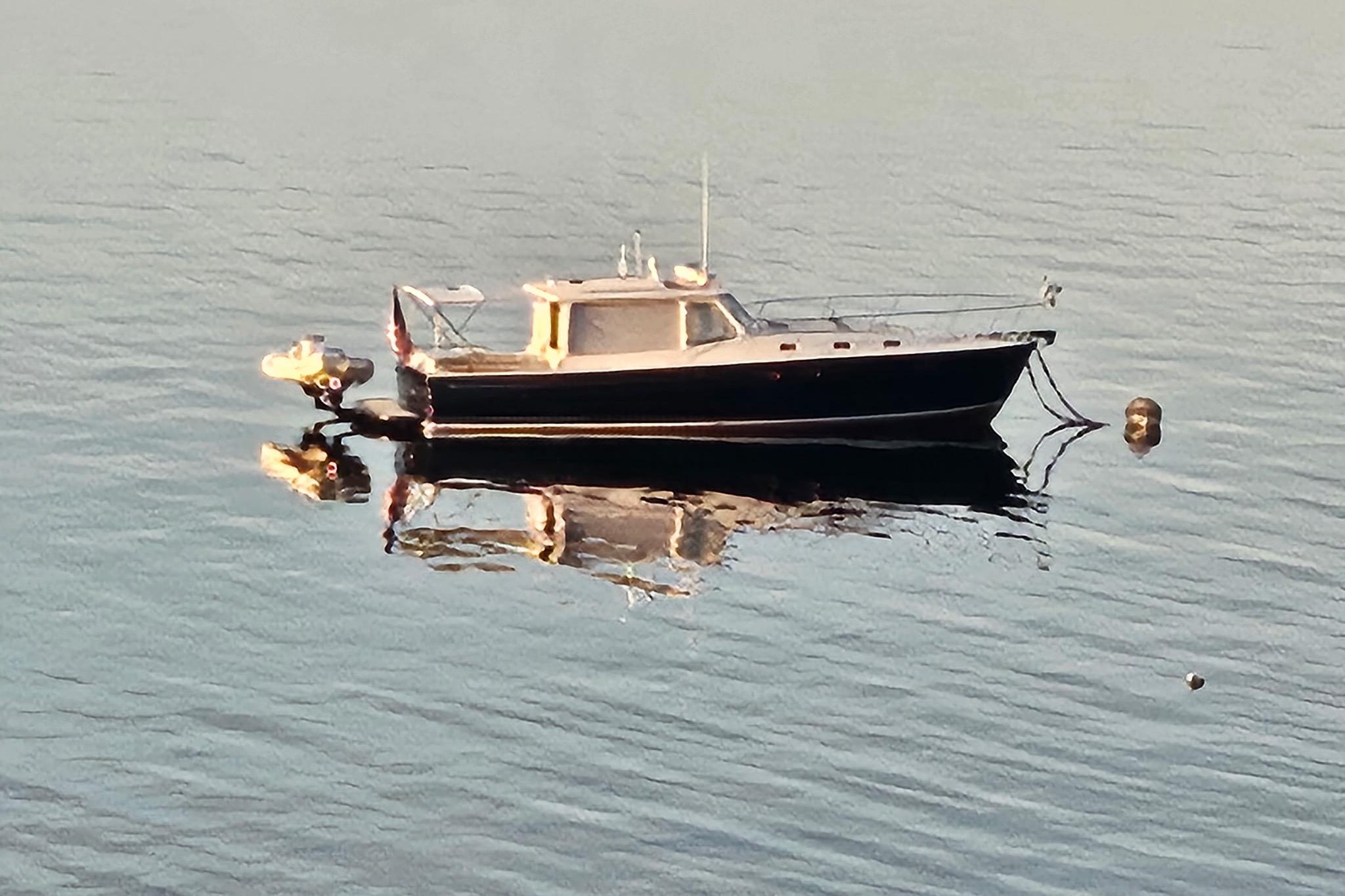 2013 MJM 40z boat floating on calm water, reflecting sunlight.