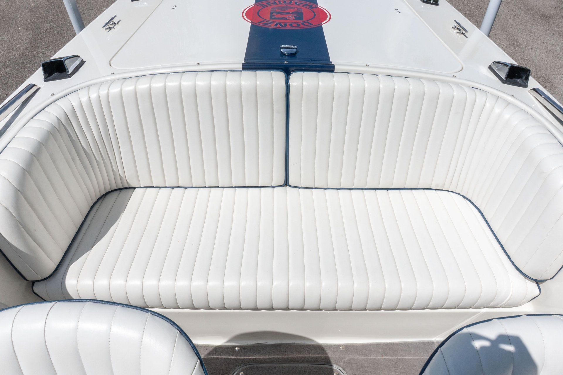 White cushioned seating on a boat with a blue stripe and red logo.