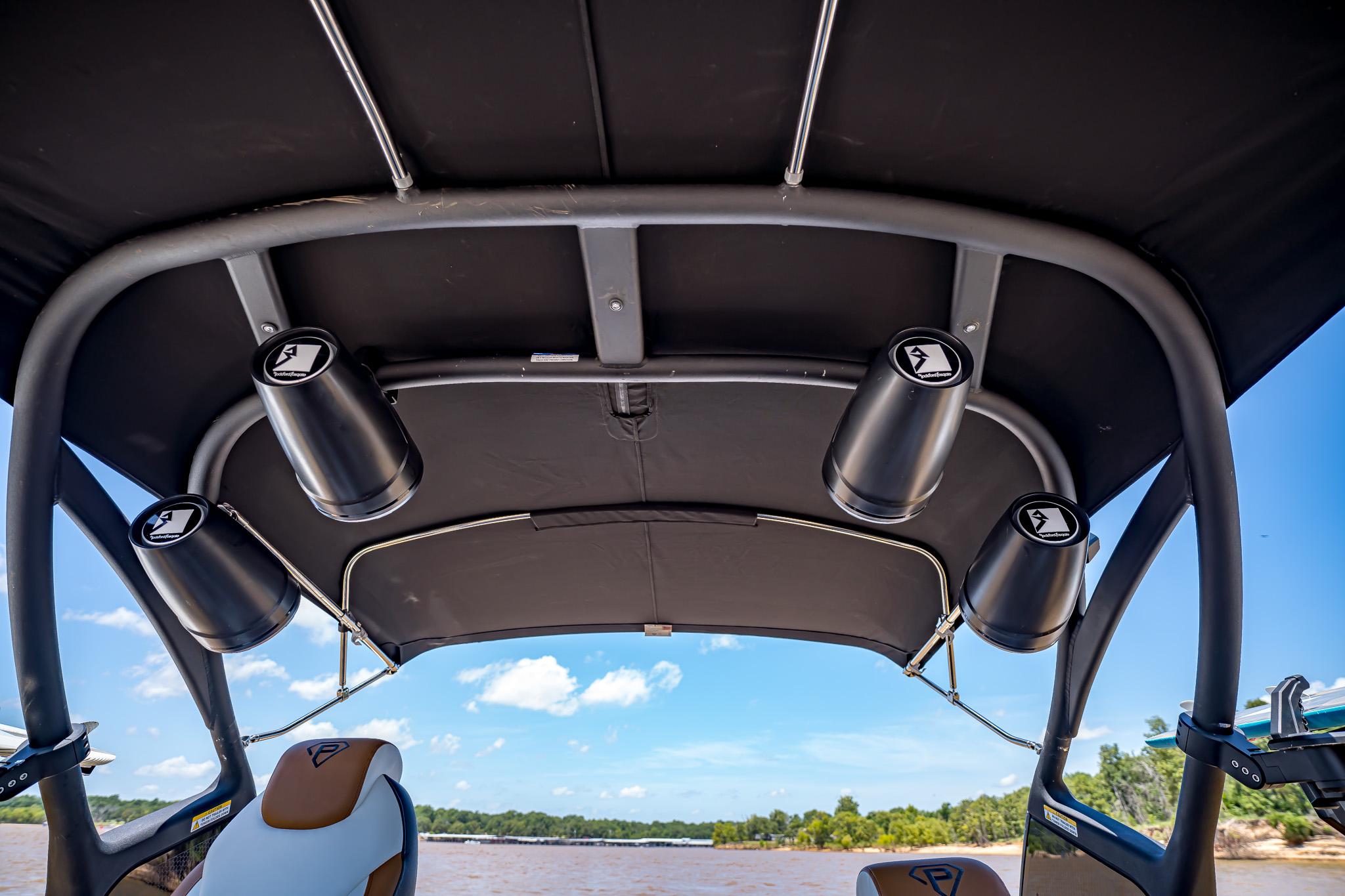 2025 Paradigm 236 boat interior with speakers and canopy, overlooking a scenic river view.