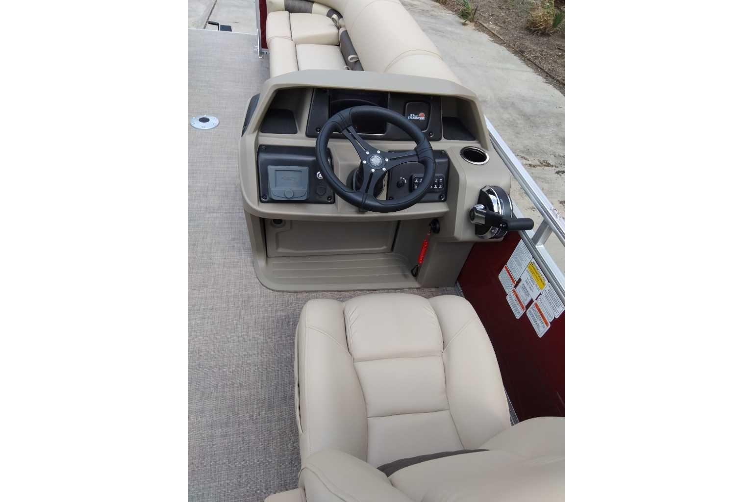 2025 Sun Tracker Party Barge 22 DLX helm with beige seating and control panel.