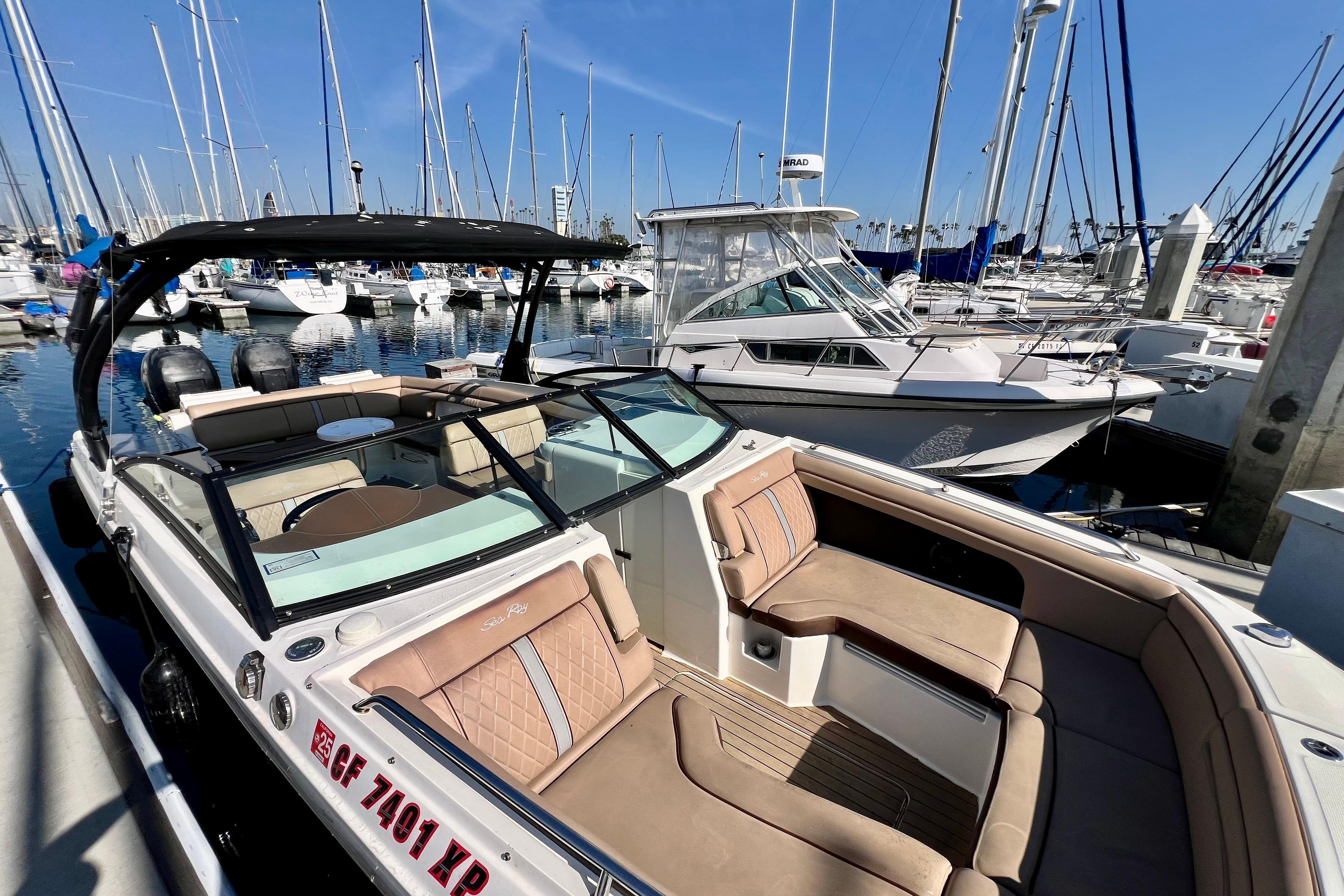 2016 Sea Ray 290 Sundeck Outboard docked in a marina, surrounded by sailboats.