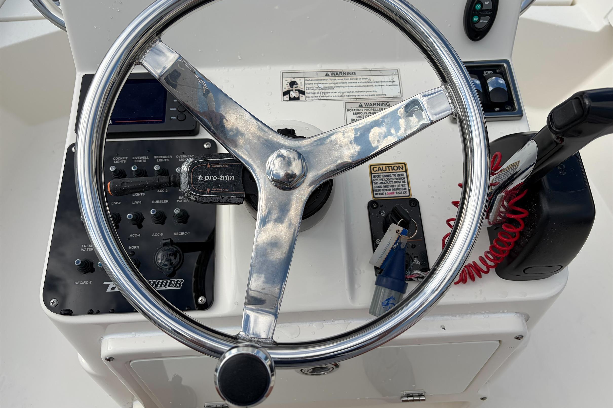 Steering console of a 2017 Pathfinder 2200 TRS boat with controls and warning labels.