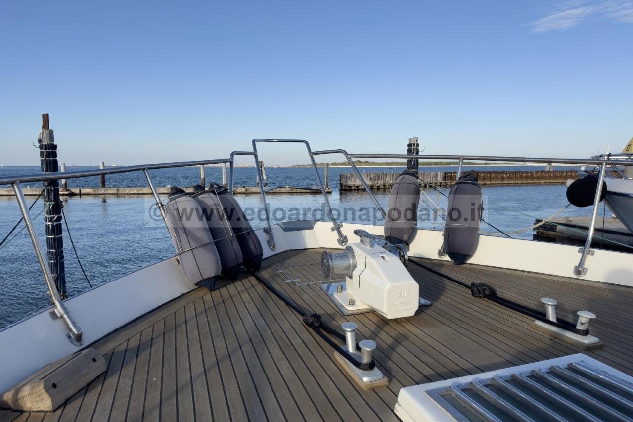 Deck view of 1973 Cantieri di Pisa Atlas yacht, featuring mooring equipment and ocean backdrop.