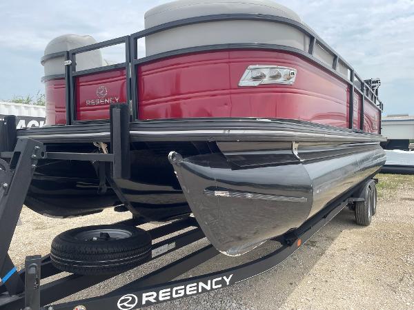 2023 Regency 250DL3 pontoon boat on trailer, red exterior, parked on gravel.