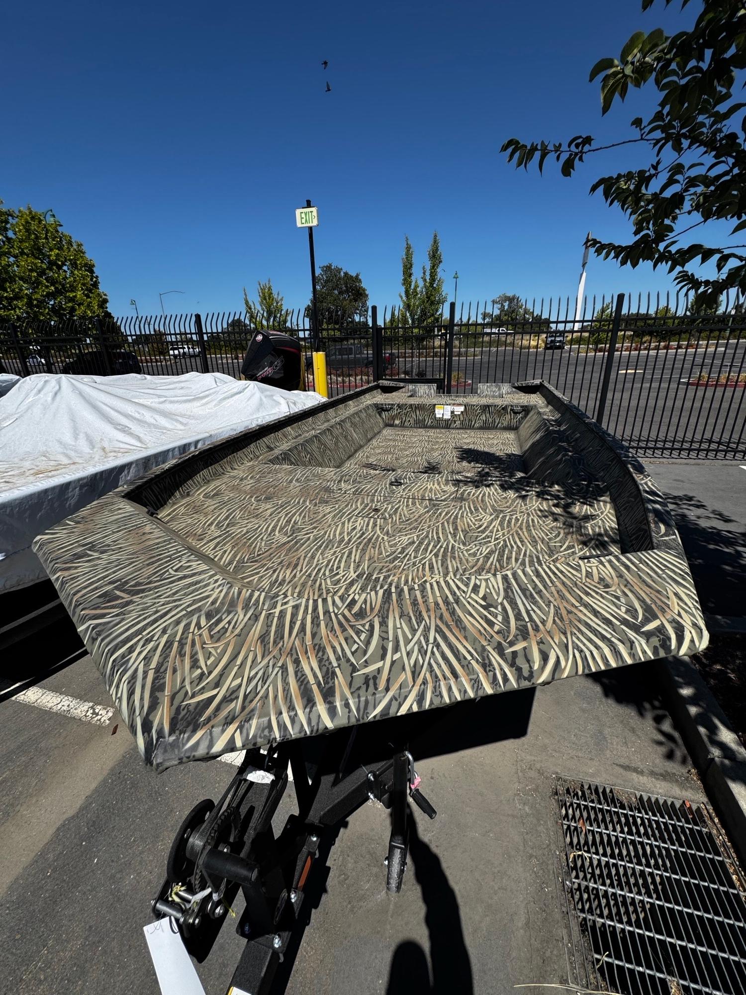2025 Tracker GRIZZLY 2072 Utility boat with camouflage pattern in a parking lot.