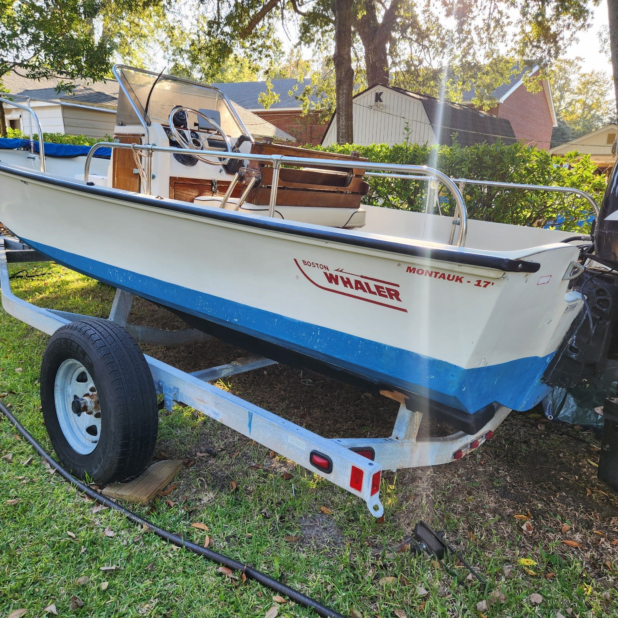 A 1976 Boston Whaler MONTAUK on a trailer outdoors, surrounded by trees.