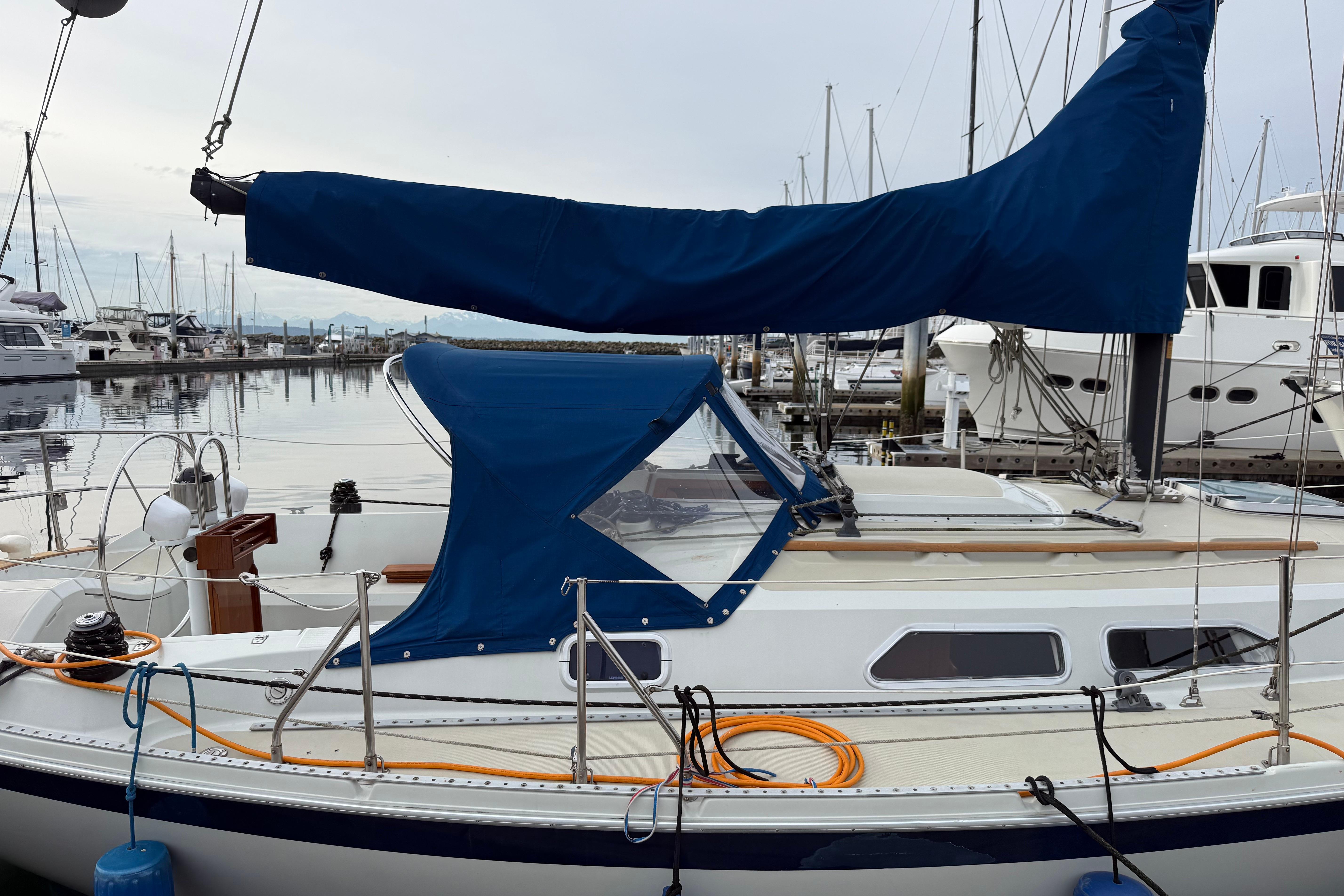1988 Ericson 32-200 sailboat docked at marina with blue sail cover.