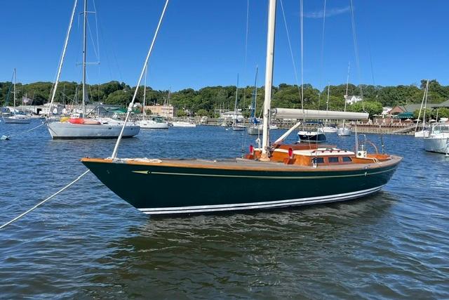 Sailboat on calm water, Morris 36 model, 2006, with scenic harbor background.