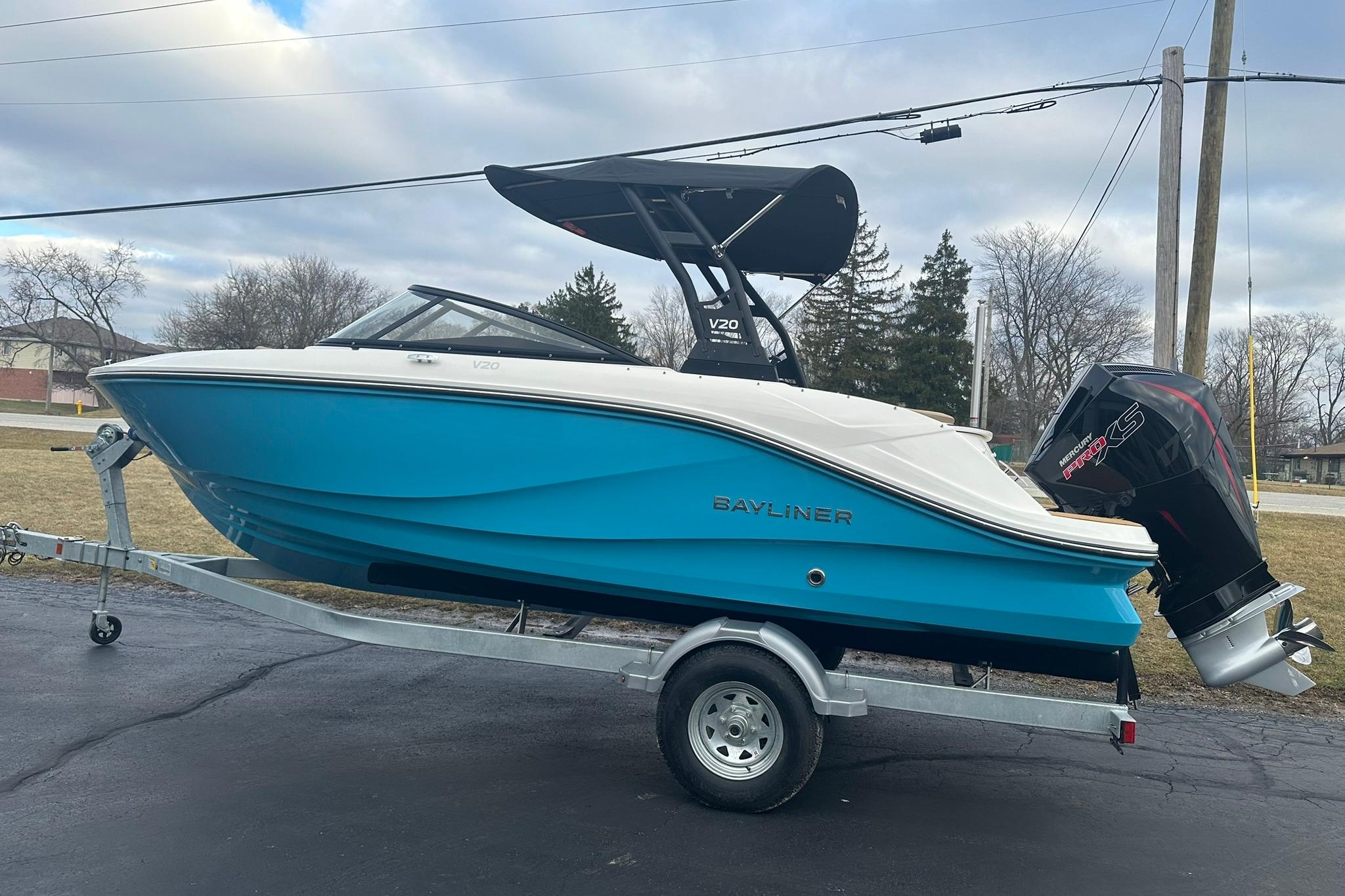 2026 Bayliner V20 boat on trailer, blue hull, outboard motor, parked outdoors.