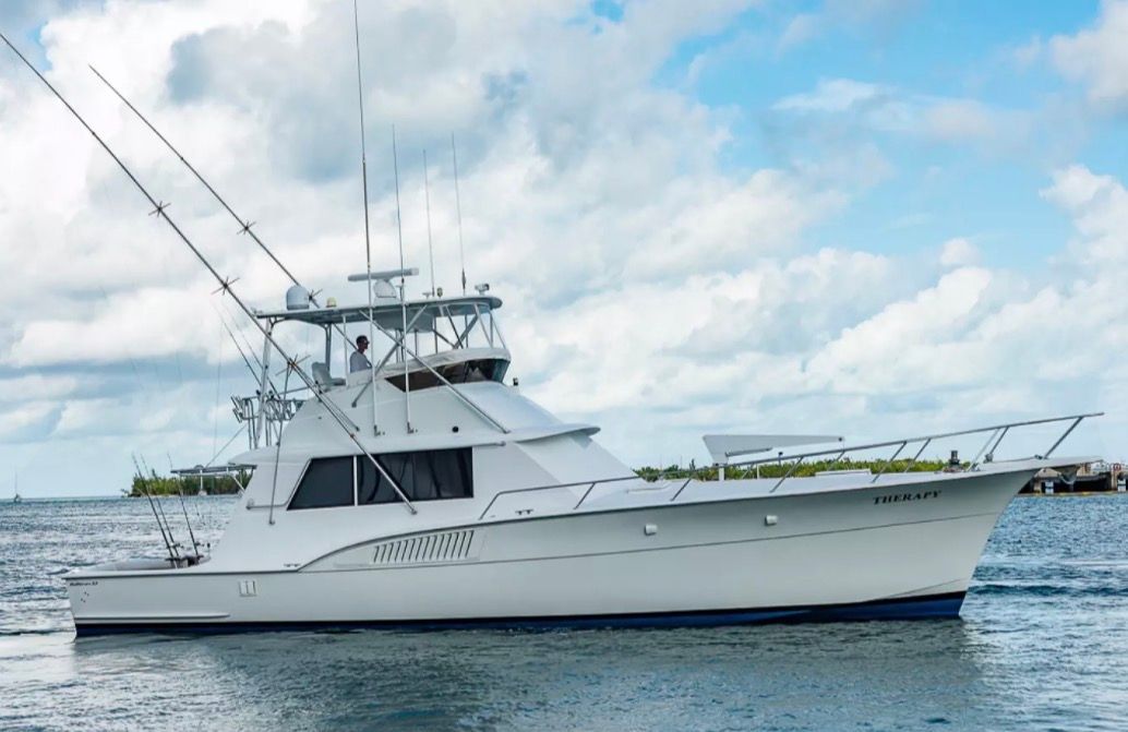 A 1979 Hatteras sport fishing boat on the water with fishing rods and a clear blue sky.