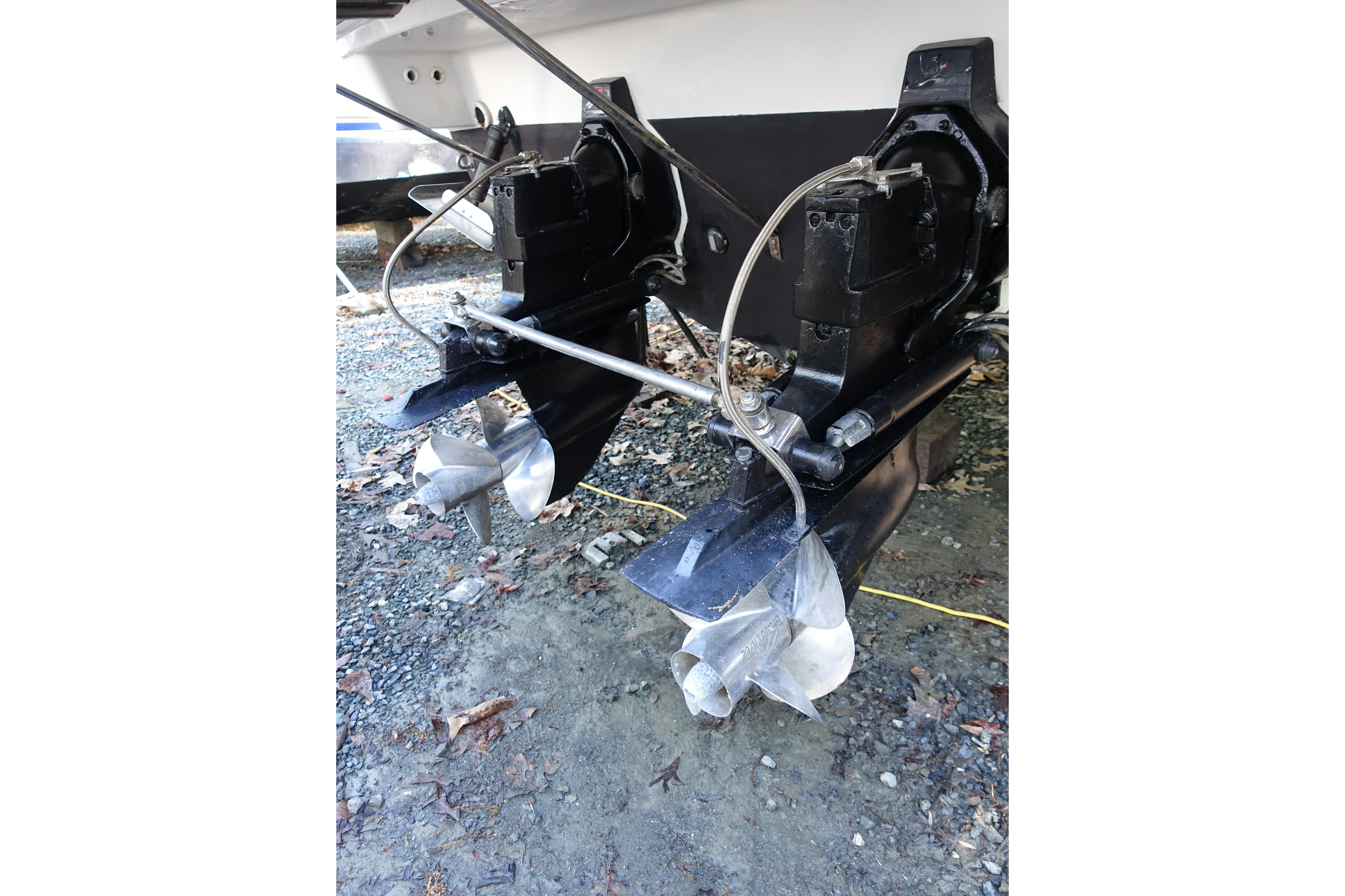 2002 Formula 330 Sun Sport boat propellers and outdrives on gravel surface.