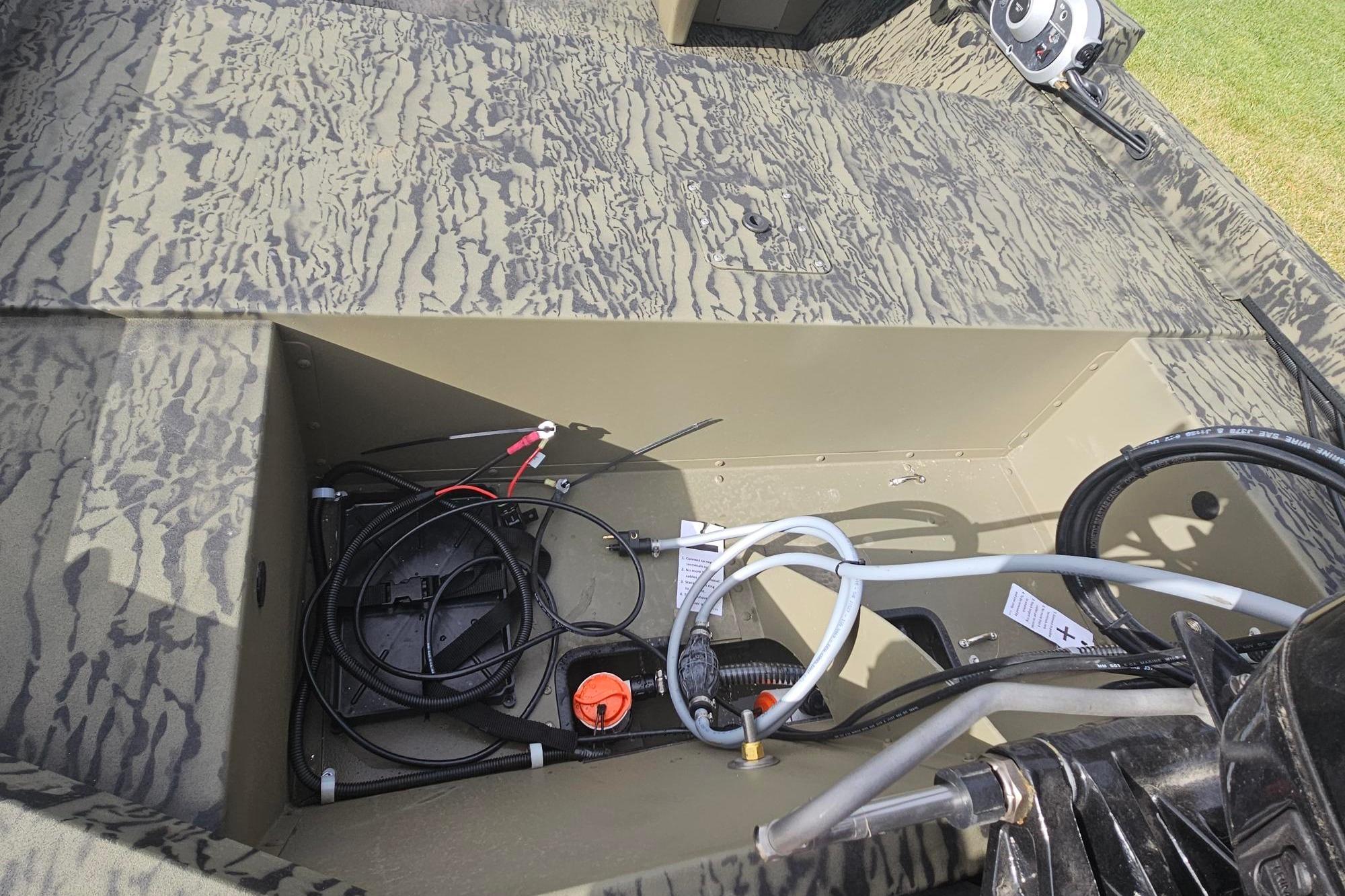 Open storage compartment in 2026 Tracker Grizzly 1648 SC boat, showing wiring and equipment.