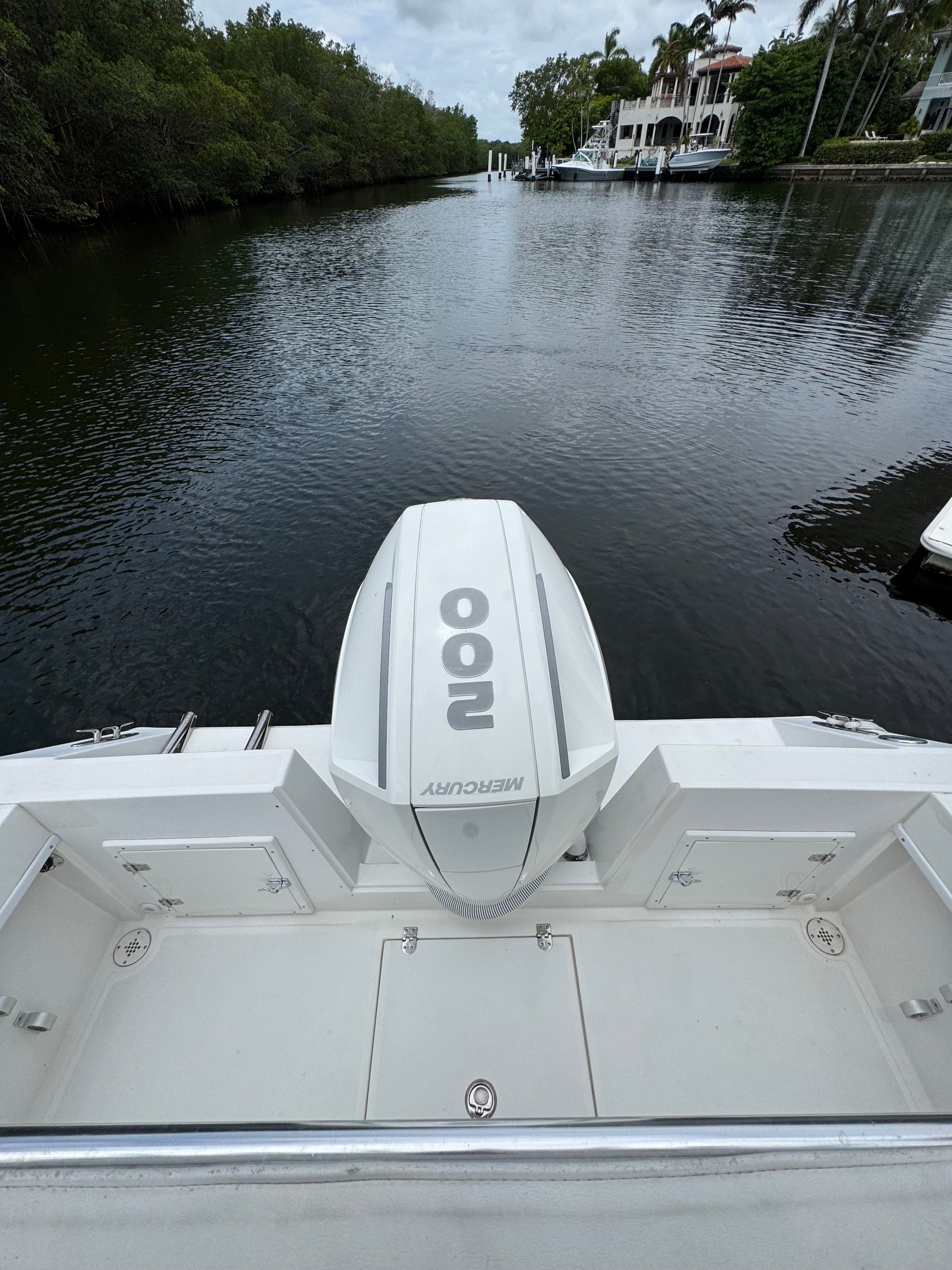 A 2004 Contender 21 boat with a Mercury 100 engine, on a calm canal.
