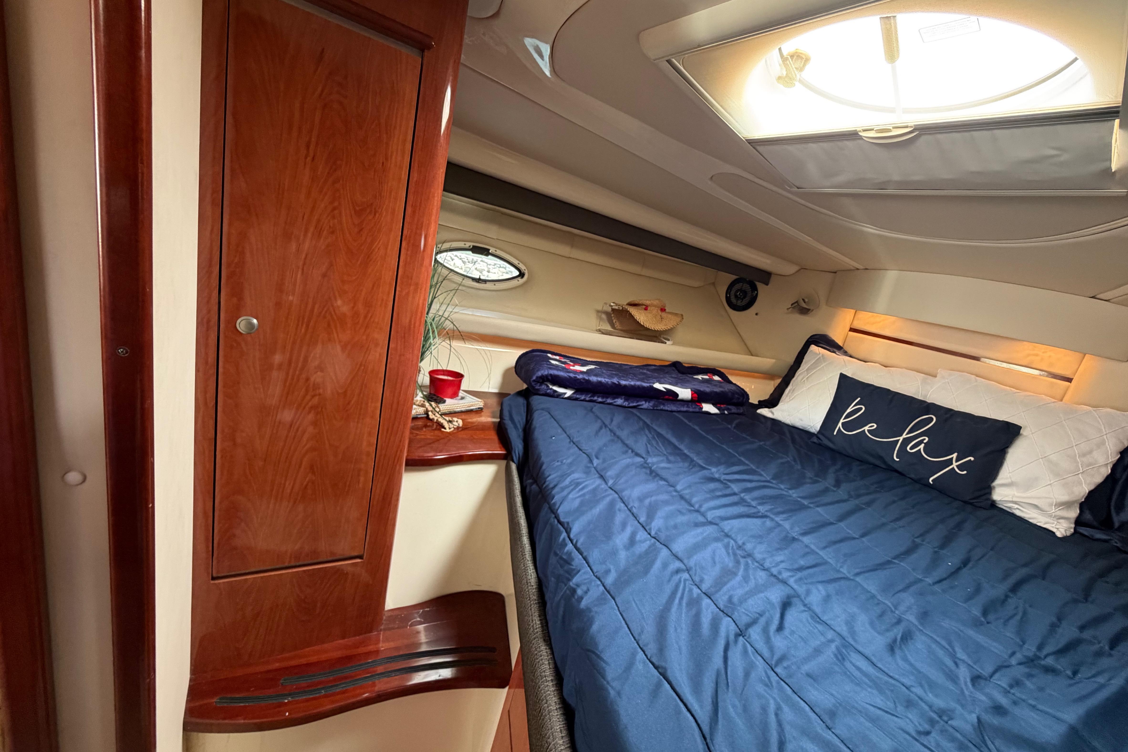 Luxurious cabin interior of 2007 Monterey 350 Sport Yacht with cozy bedding and wooden cabinetry.