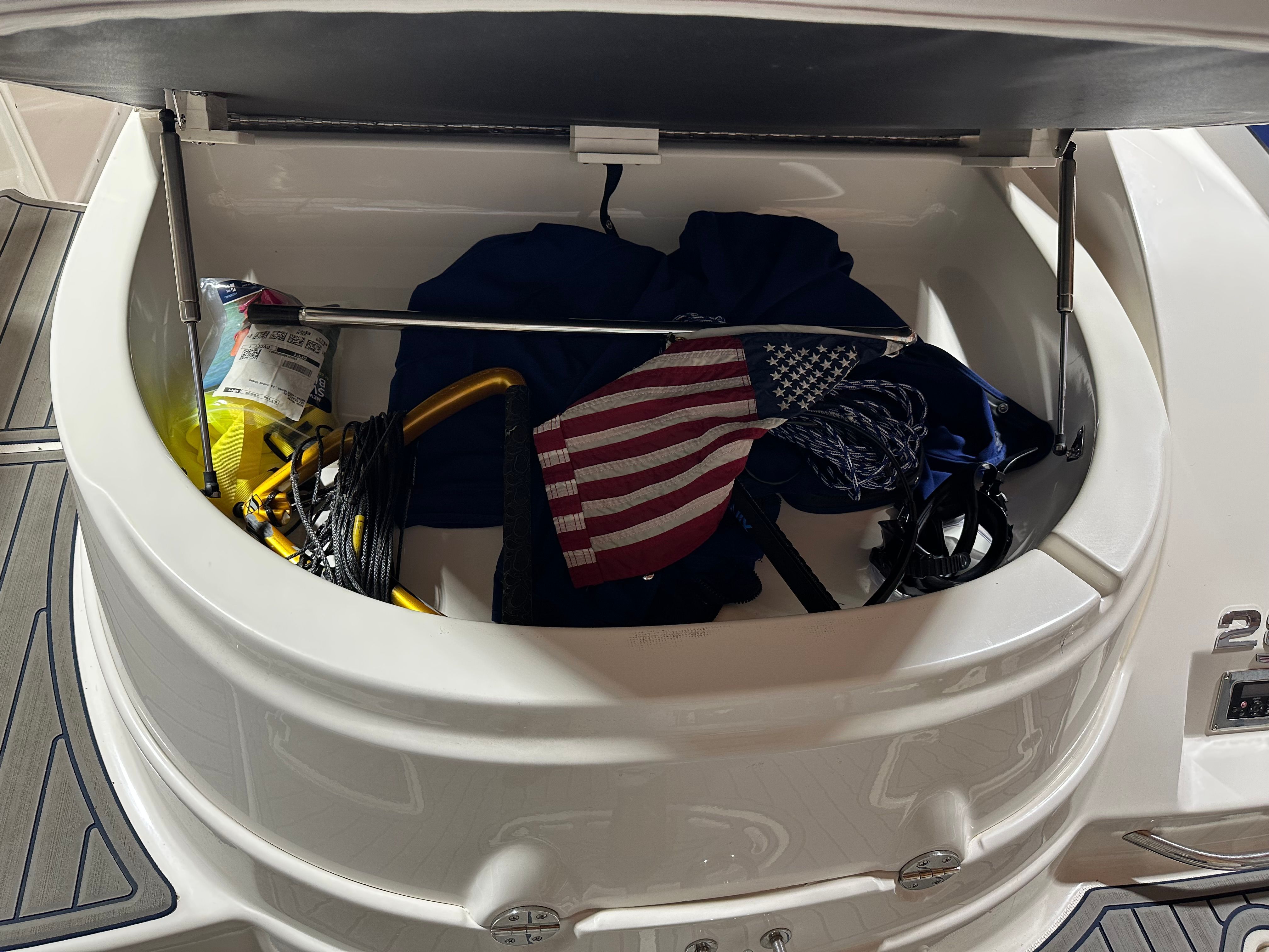 An open storage compartment on a boat with an American flag and ropes.