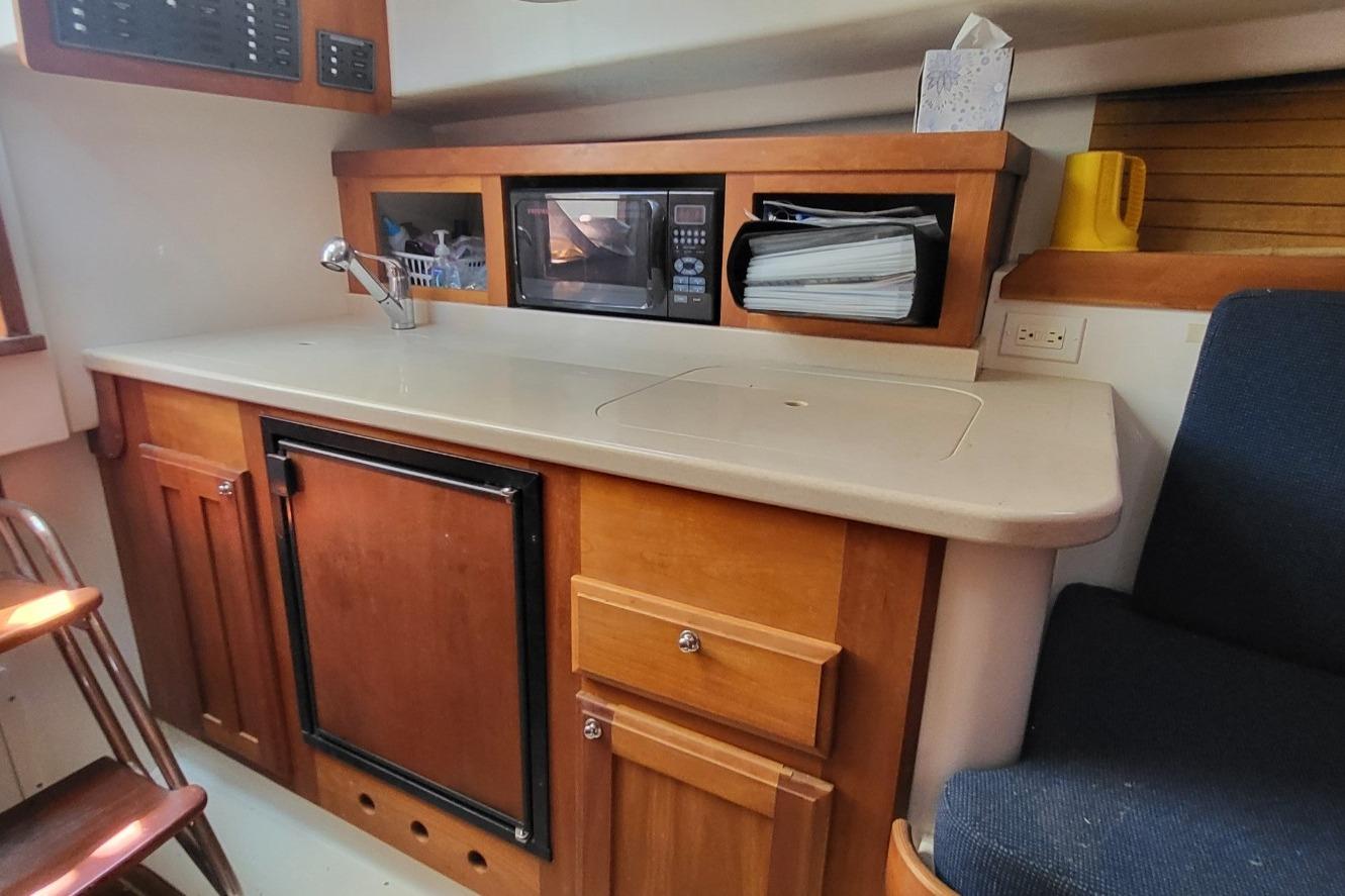 2006 Back Cove 29 boat interior with kitchenette, featuring a microwave, sink, and storage cabinets.
