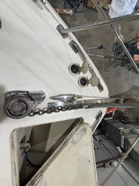 Close-up of the anchor and chain on a boat, with deck details and metal railing.