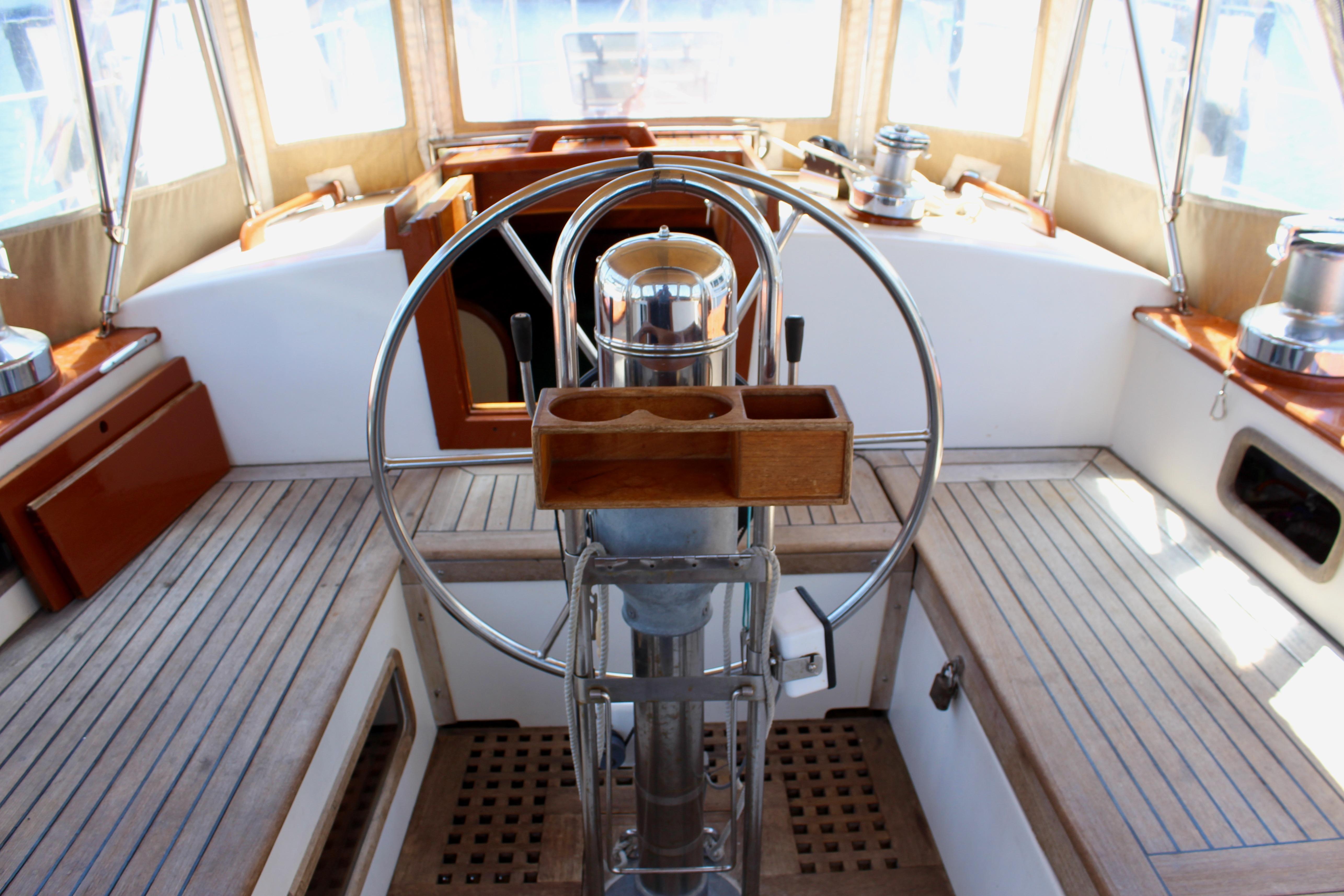 Cockpit of a 1981 Kelly Peterson 46 sailboat with wooden and metal steering wheel.