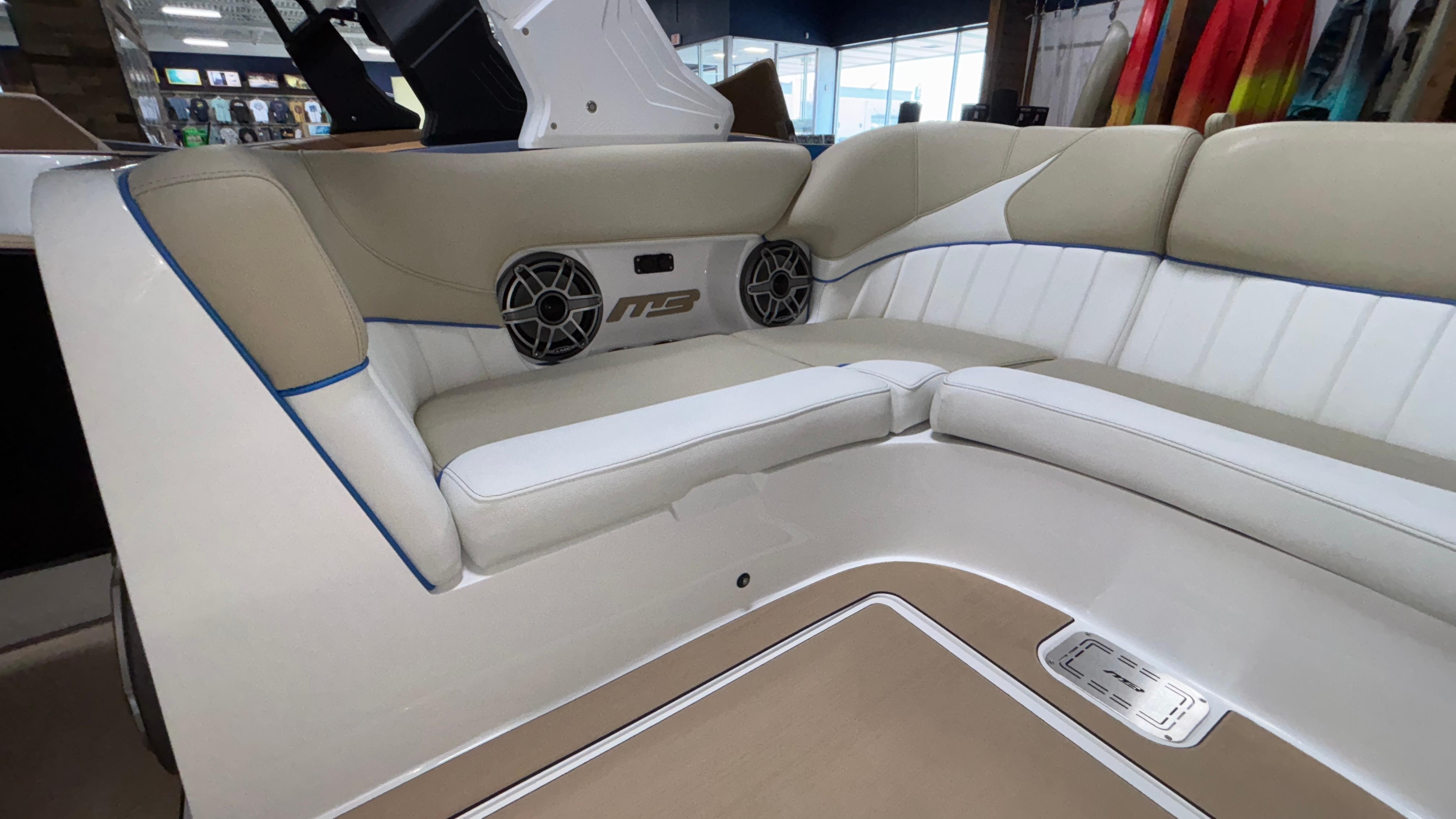 2025 MB B52 23 Classic boat interior with beige and white seating, featuring built-in speakers.