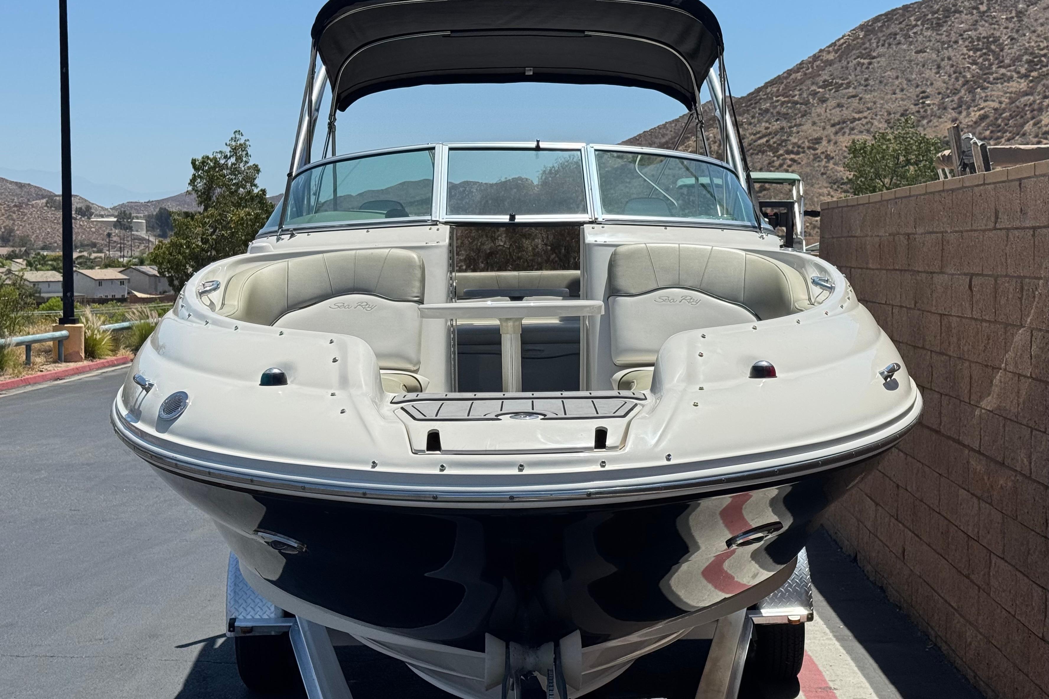 2007 Sea Ray 240 Sundeck boat on trailer, parked near a brick wall.