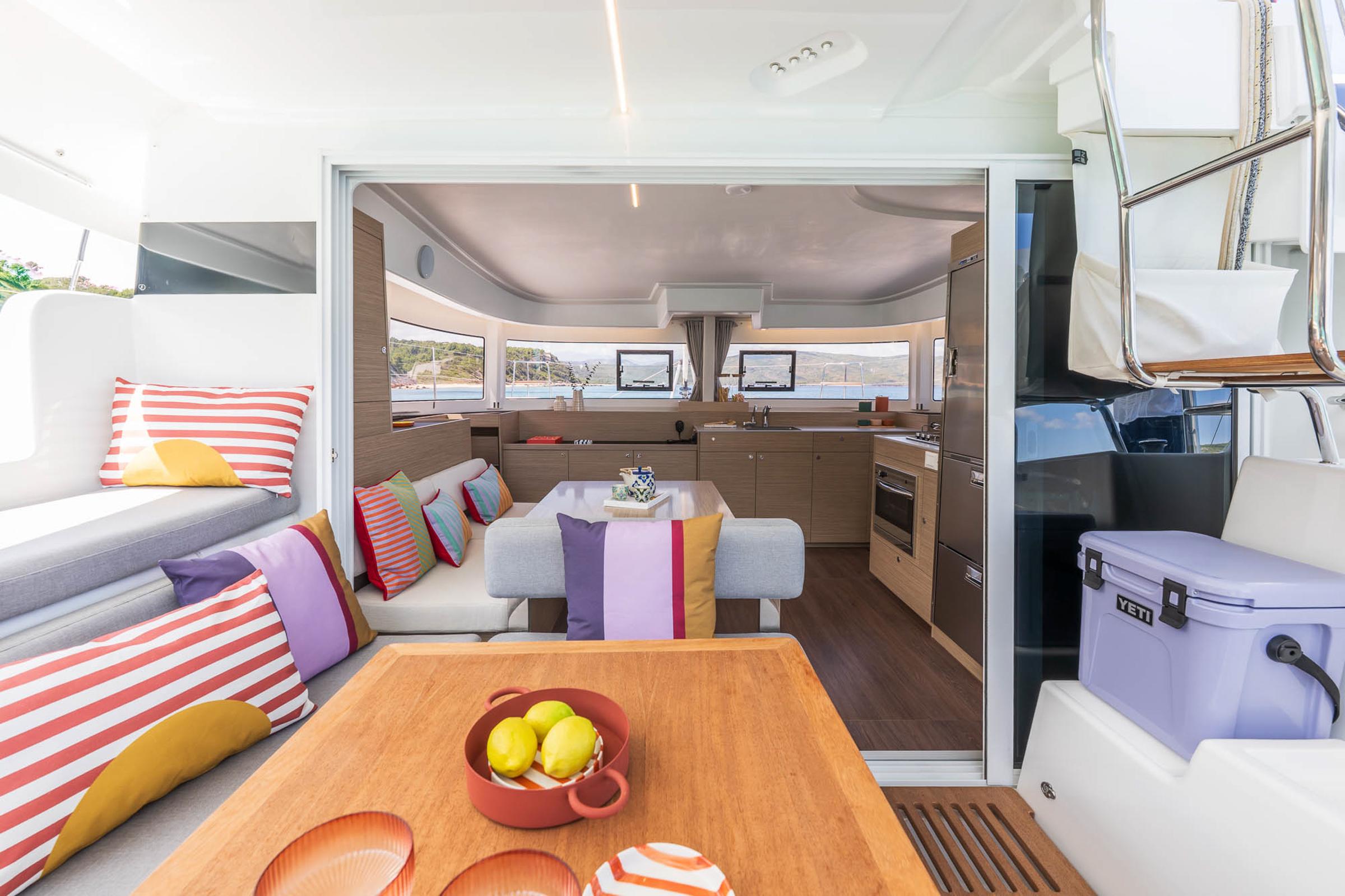Luxurious interior of 2025 Lagoon 38 catamaran with colorful cushions and modern kitchen.
